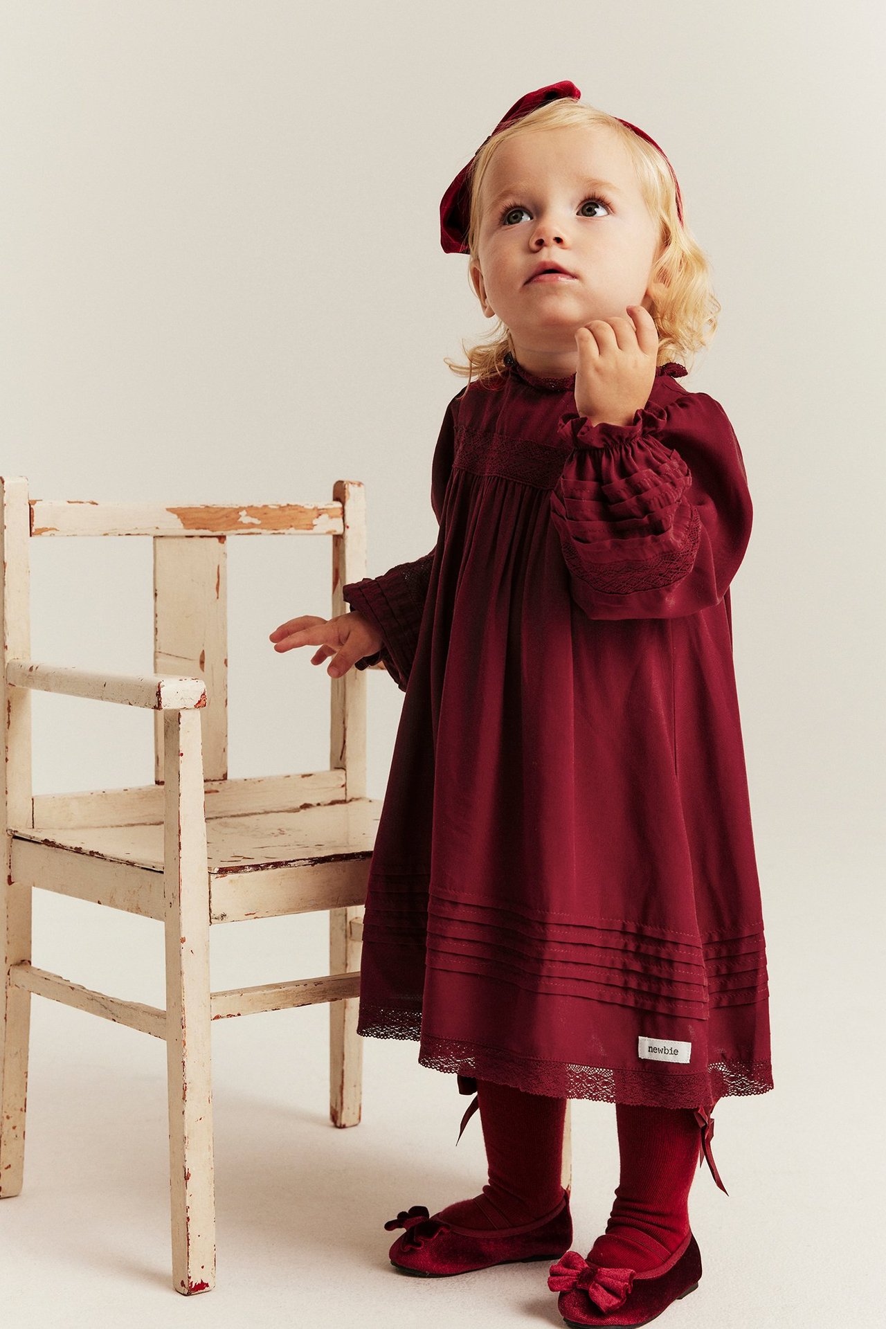 Little girl in red viscose dress with lace, pintucks, elastic sleeves, back opening, model interaction.