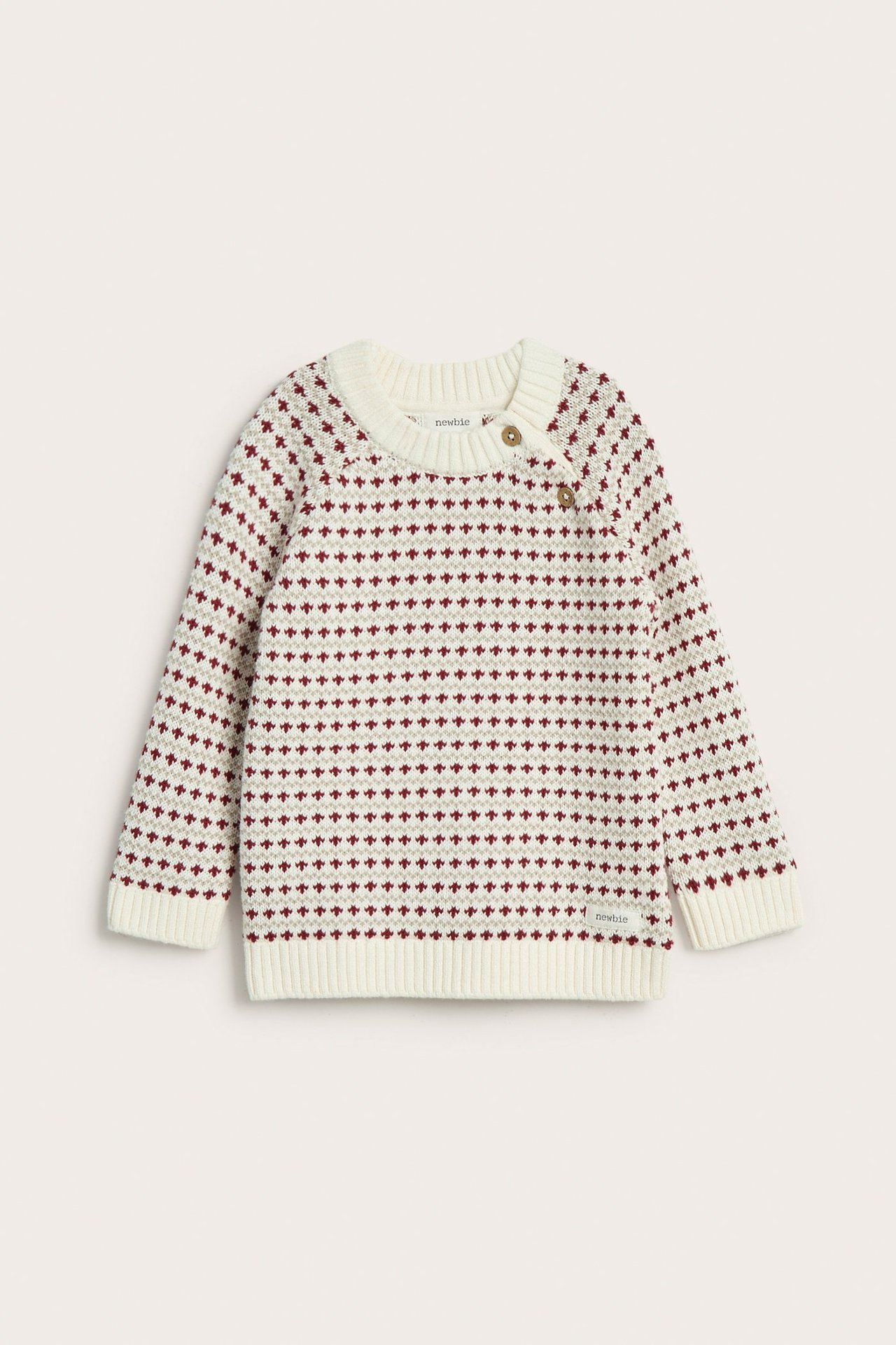Vorderansicht eines beigen Kinder-Baumwollstrickpullovers mit rotem Jacquardmuster und zwei Schulterknöpfen.