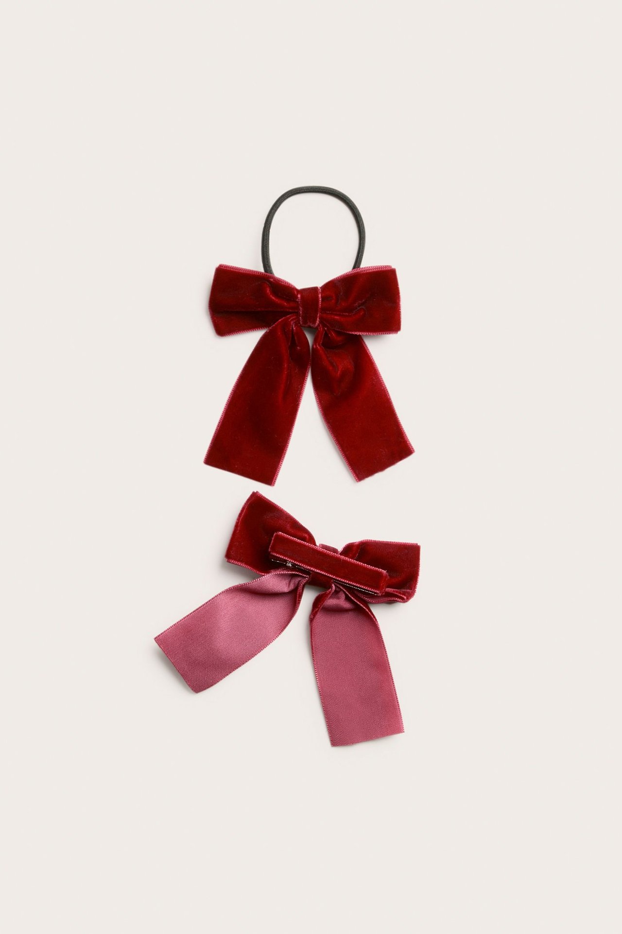 Close-up front view of two red velvet bows, one with an elastic and one with a clip.
