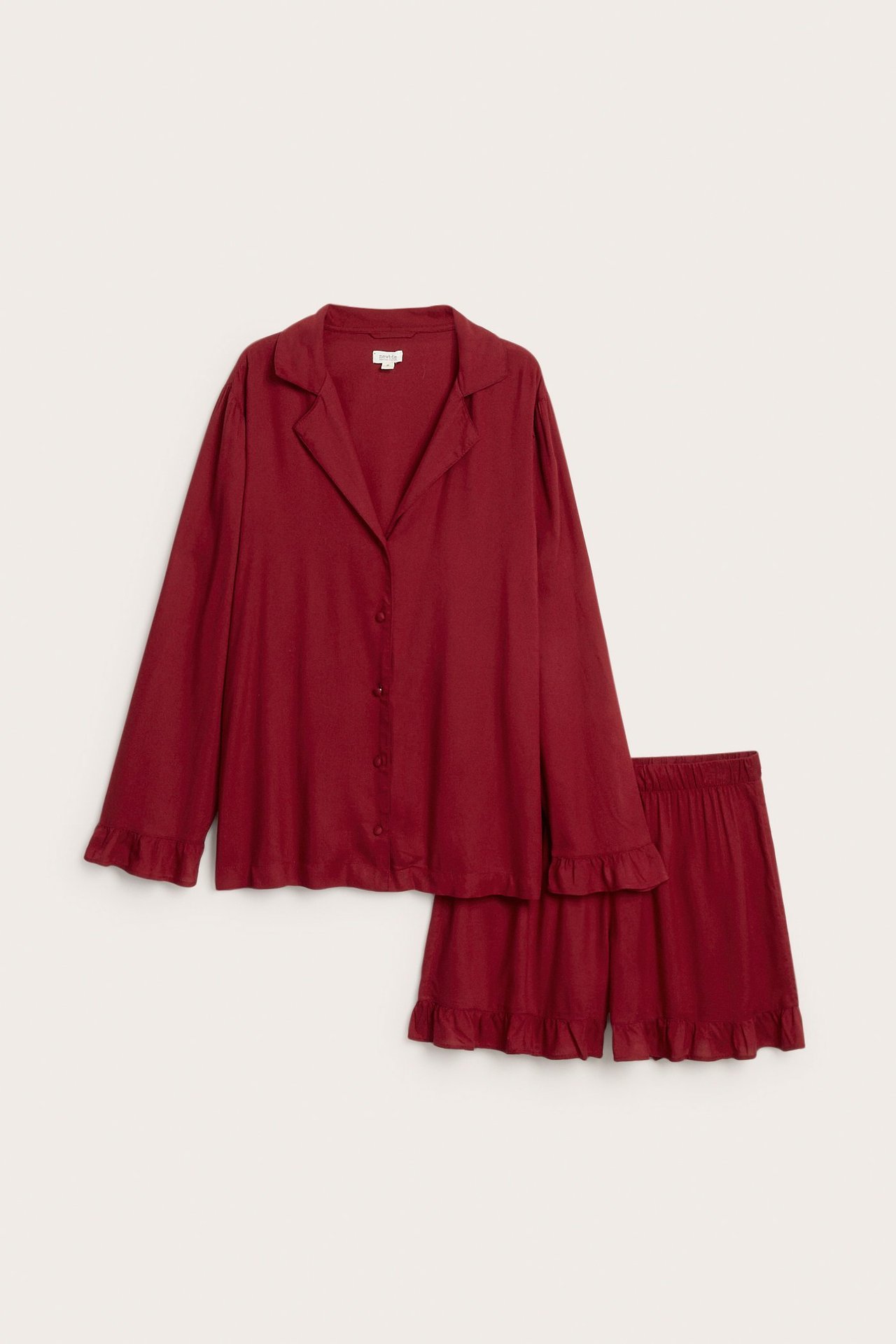 Front view of a plain red woven viscose women's pyjama set with collared shirt and ruffled shorts.