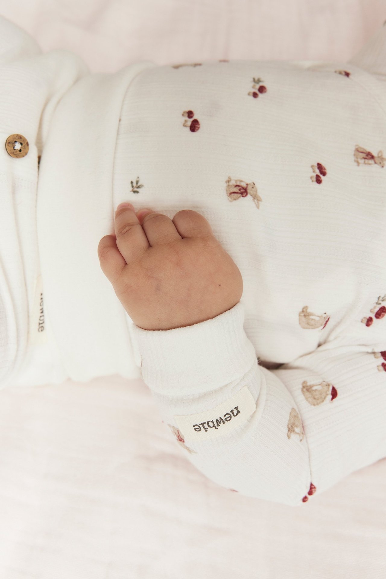 Nahaufnahme eines Babys in einem cremefarbenen, langärmeligen Wickelbody mit Tiermuster.