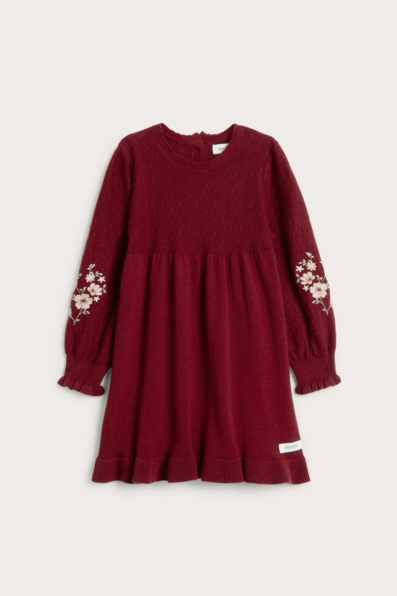 Front view: red knitted kid's dress with embroidered sleeves, ribbed cuffs, flounce hem, and back buttons.