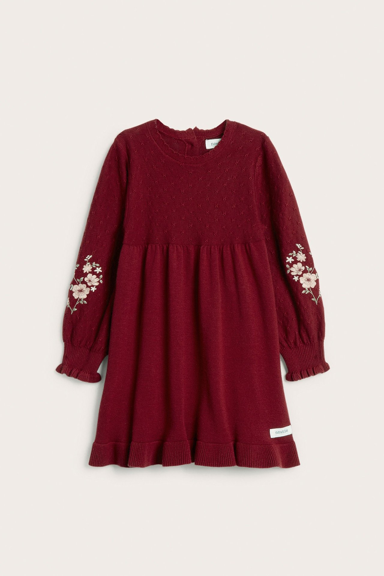 Front view: red knitted kid's dress with embroidered sleeves, ribbed cuffs, flounce hem, and back buttons.