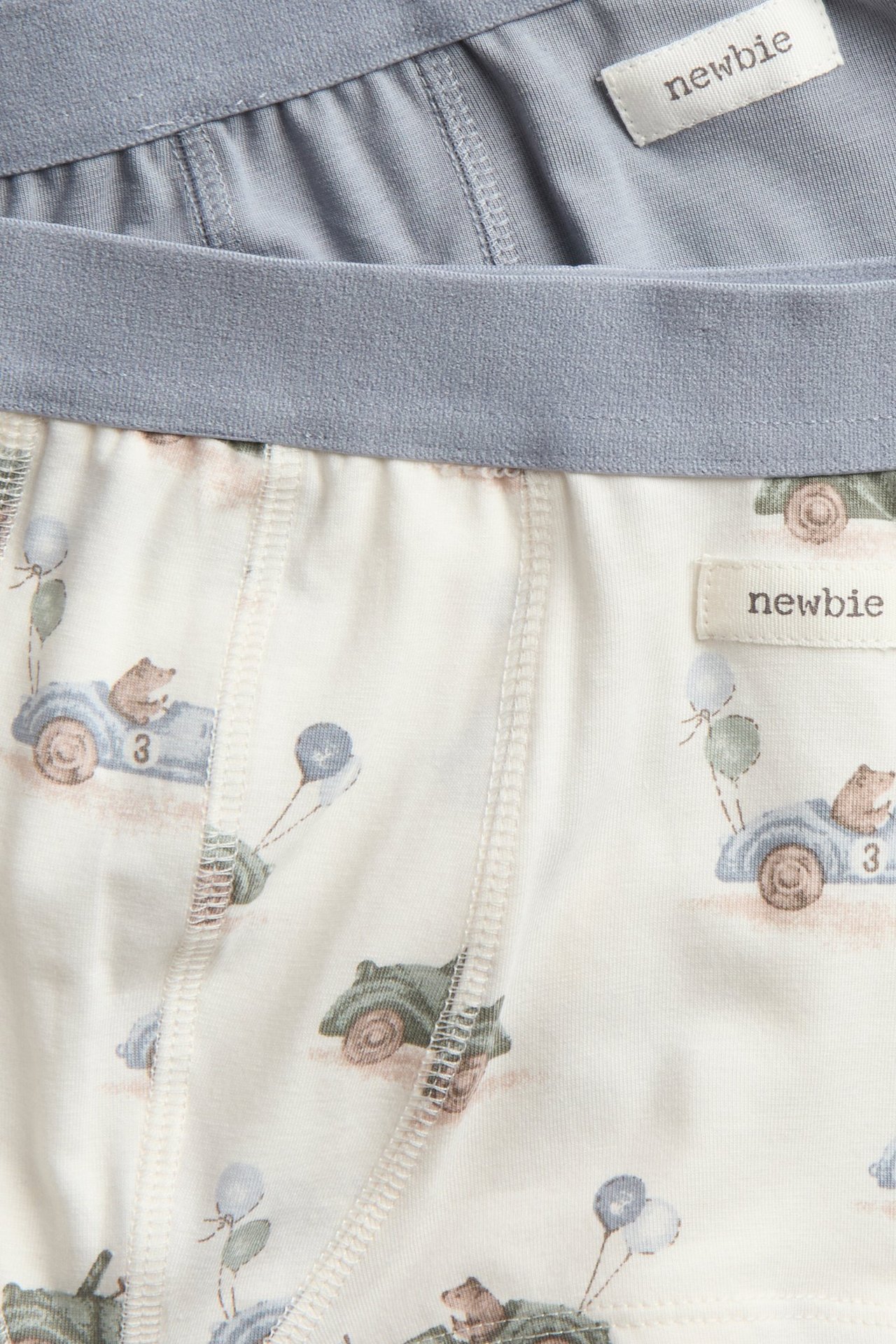 Nahaufnahme von Kinder-Boxershorts aus Jersey: ein Paar cremefarben mit Teddy-Auto-Muster, ein Paar hellblau.