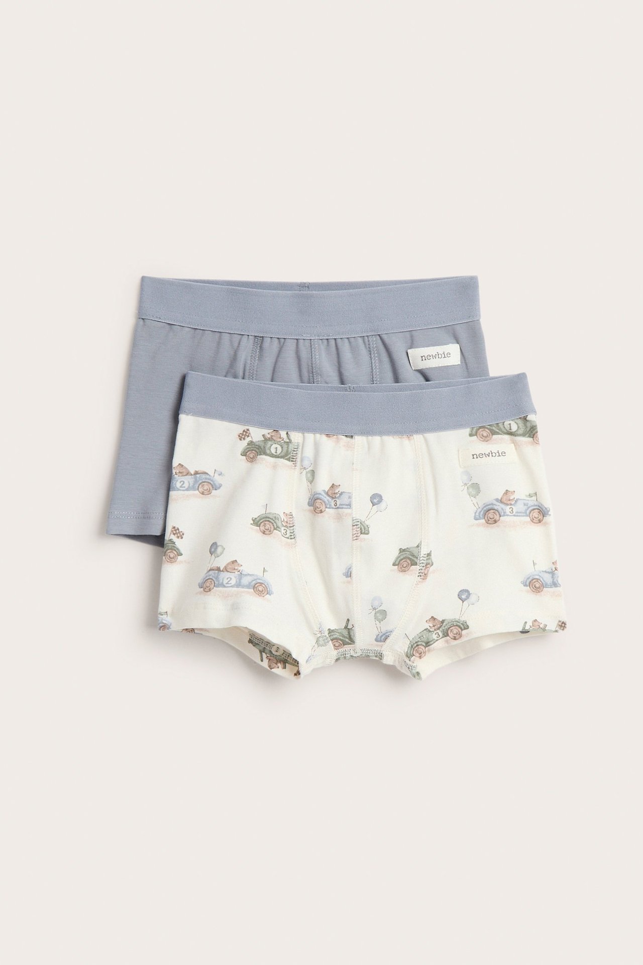 Vorderansicht: zwei Kinder-Boxershorts. Eine cremefarben mit Automuster, eine einfarbig hellblau.
