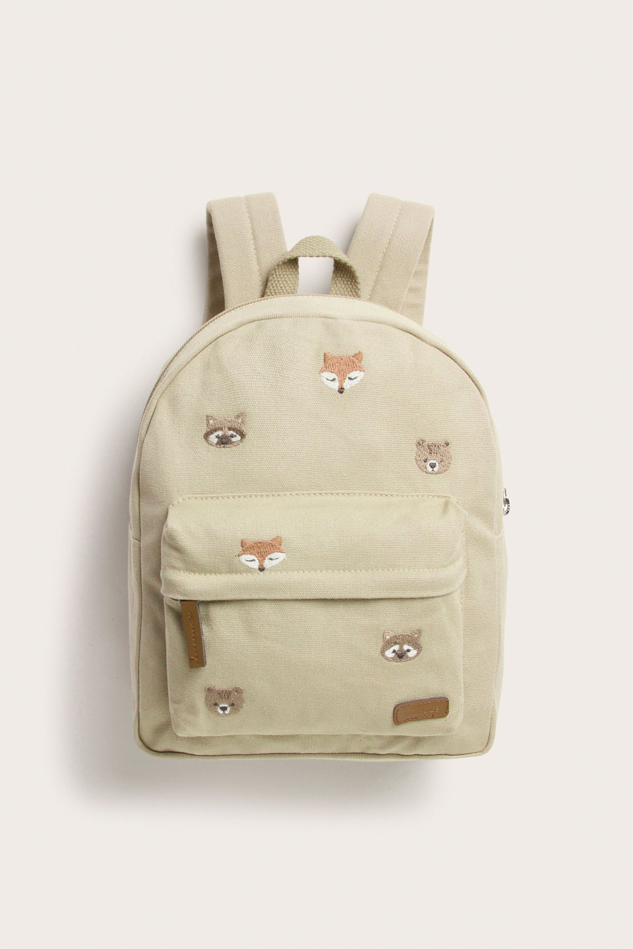 Vorderansicht eines beigen Baumwoll-Rucksacks mit gestickten Tiergesichtern, Fronttasche und Reißverschlüssen.