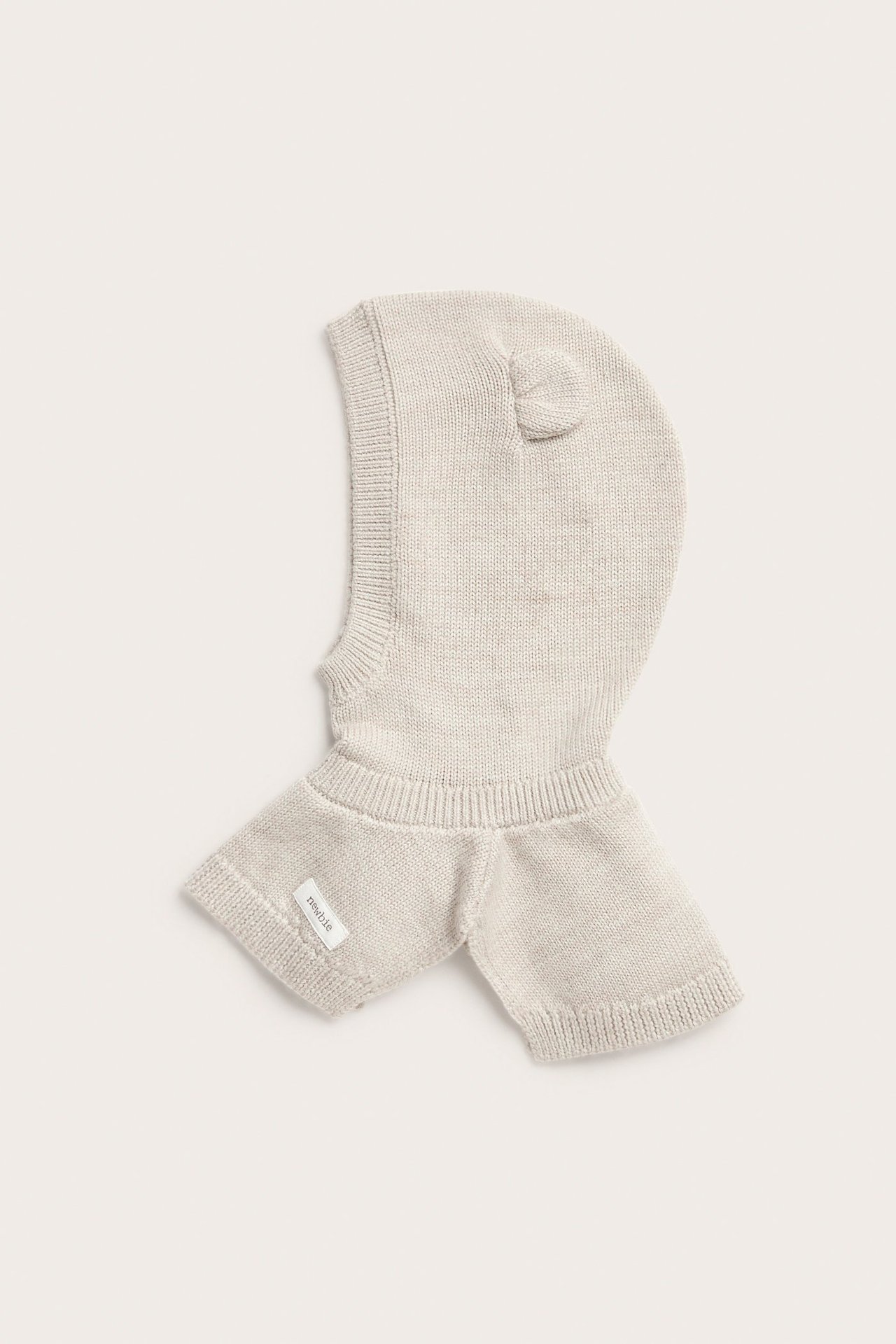 Vorderansicht einer beigen Baby-Sturmhaube aus 100% Wolle mit kleinen Ohren und Rippenbündchen.