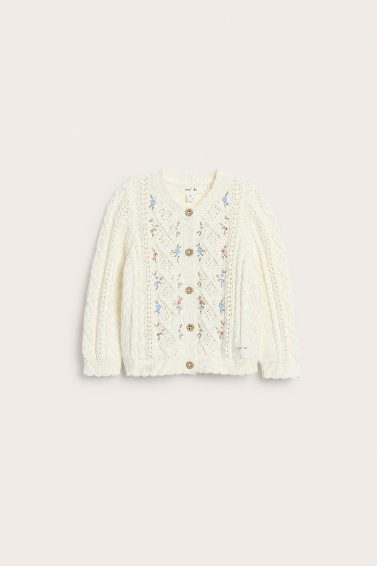 Front view: Off-white cotton knit cardigan with floral embroidery, cable knit sleeves, wooden buttons, and scalloped edges.