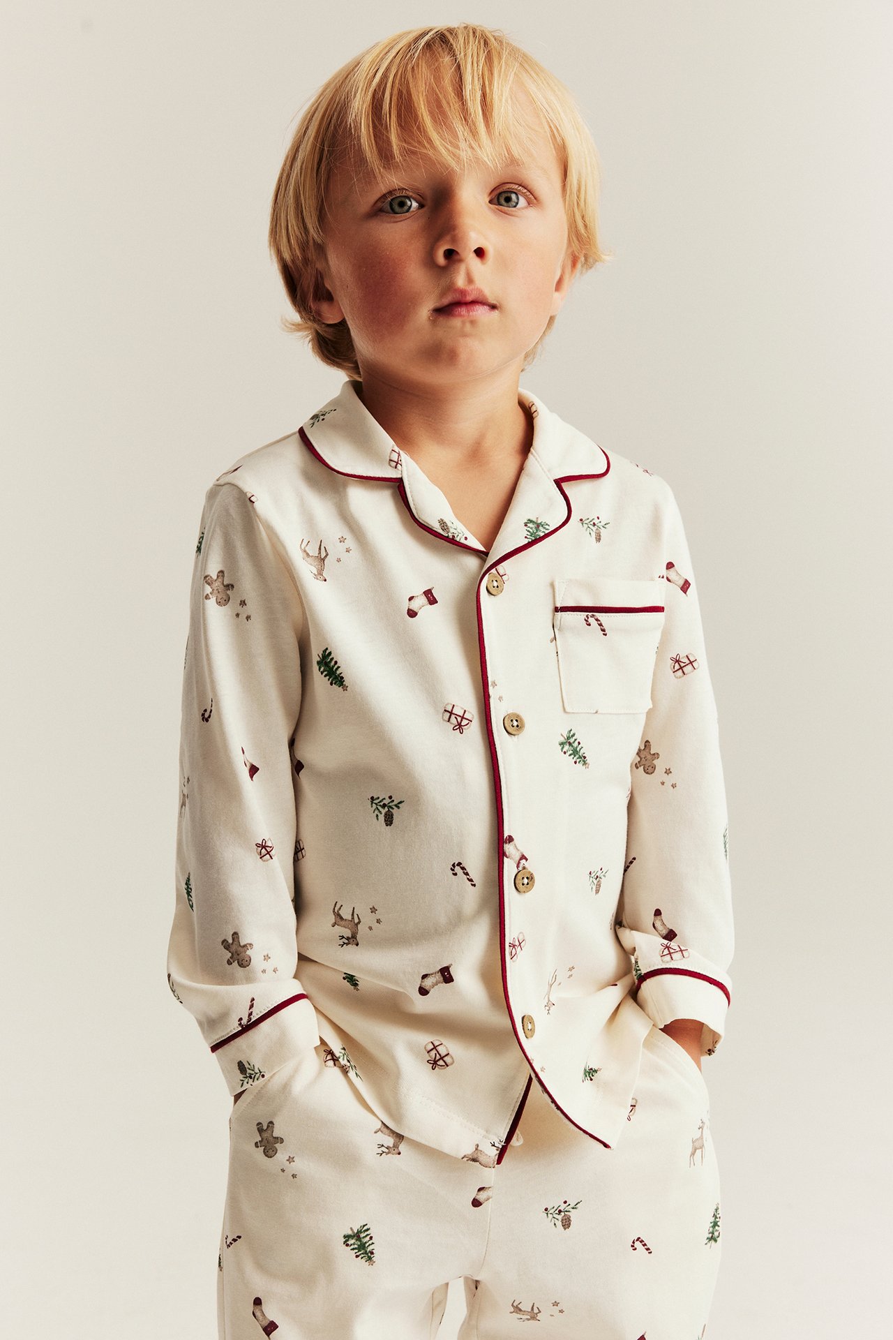 Kind in weißer Weihnachts-Pajamas mit Muster, Knöpfe vorne, lange Ärmel, elastische Hosen.