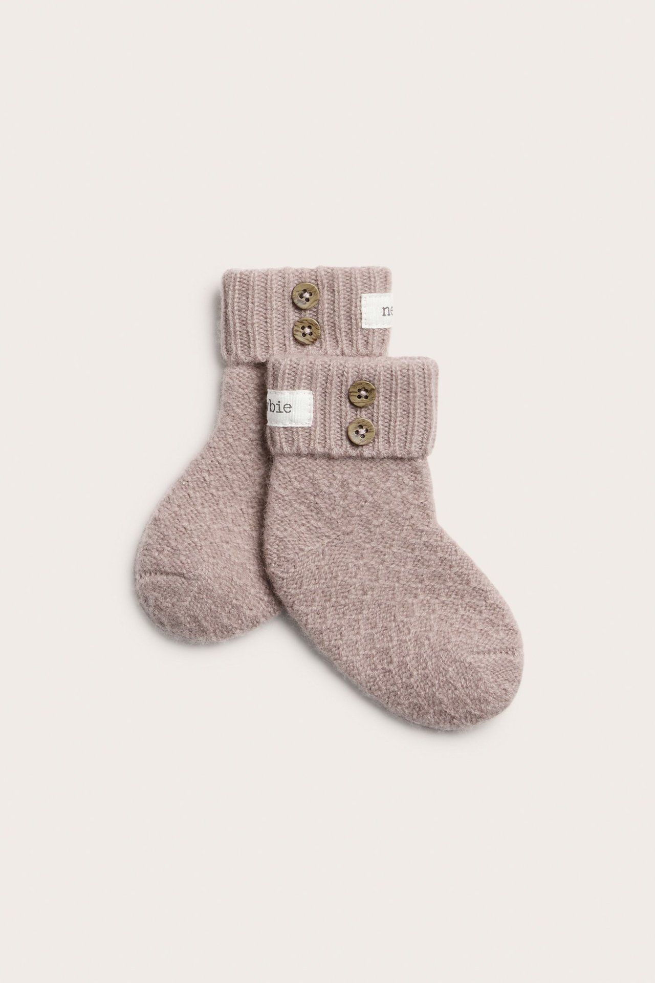 Top view of two pink baby booties in wool-cashmere blend, with ribbed folded cuffs and two brown buttons.