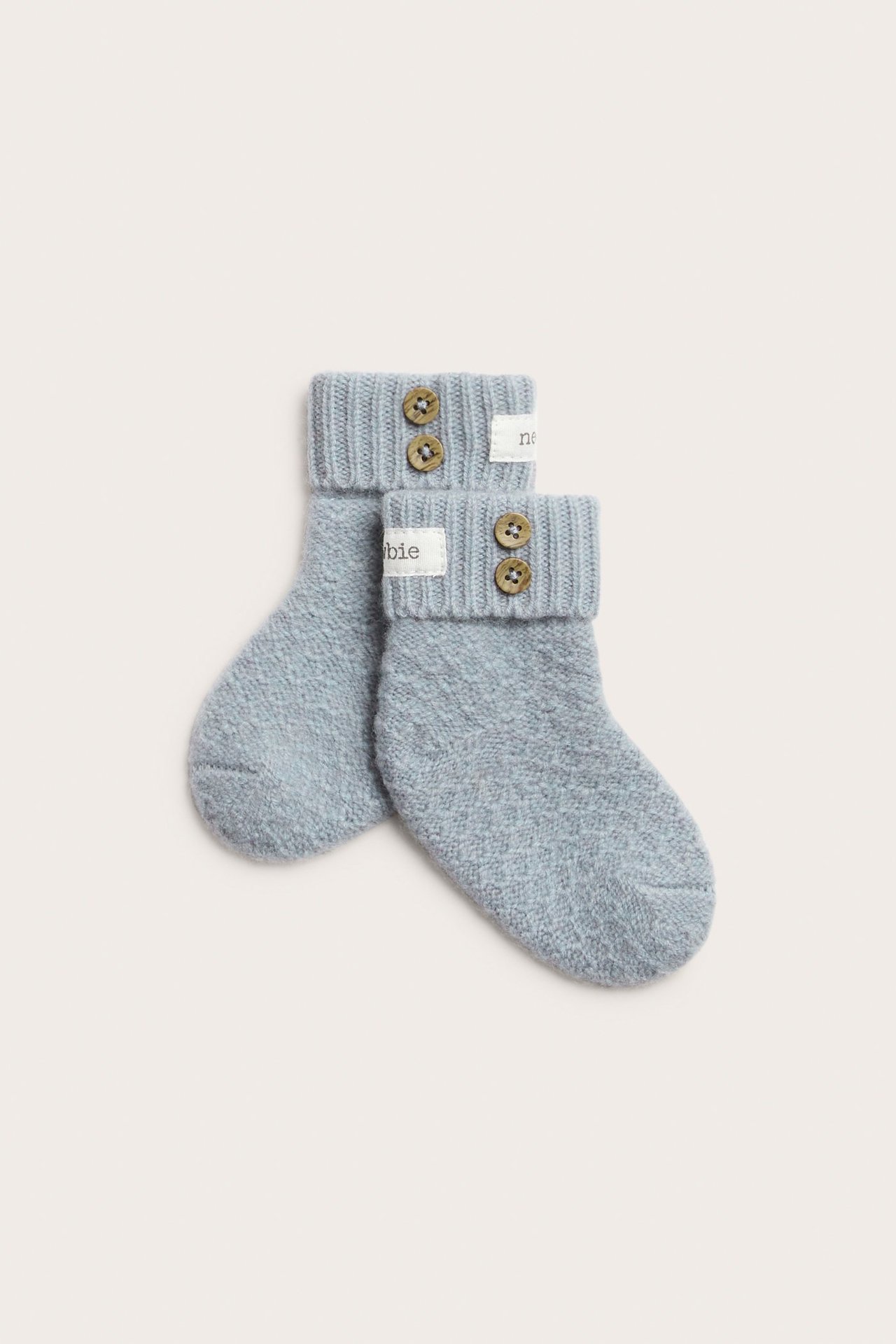 Front view of light blue baby booties in wool-cashmere blend with ribbed cuffs and decorative brown buttons.