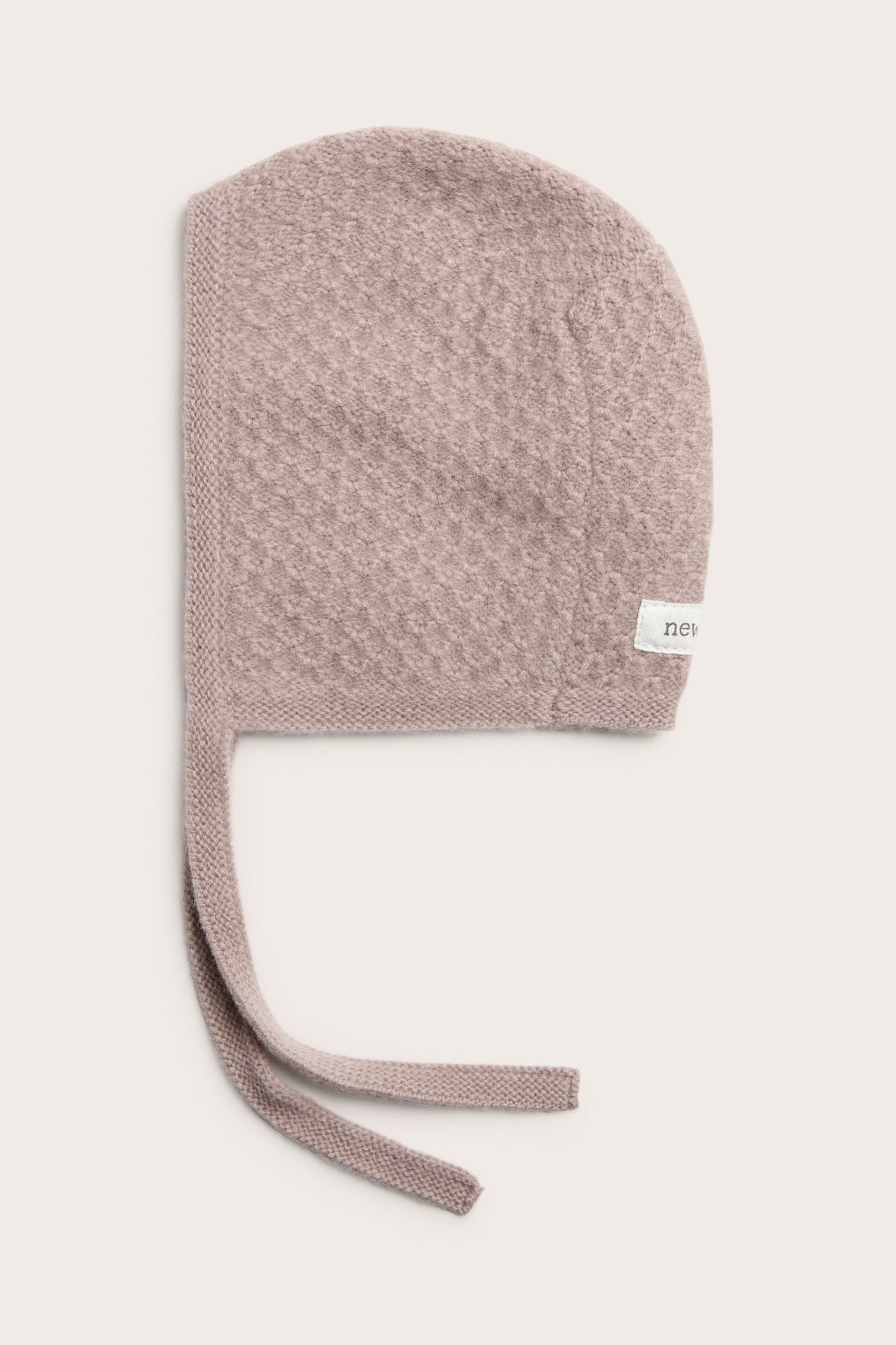 Front view of a pink baby bonnet in a textured wool and cashmere knit, with tie-strings.