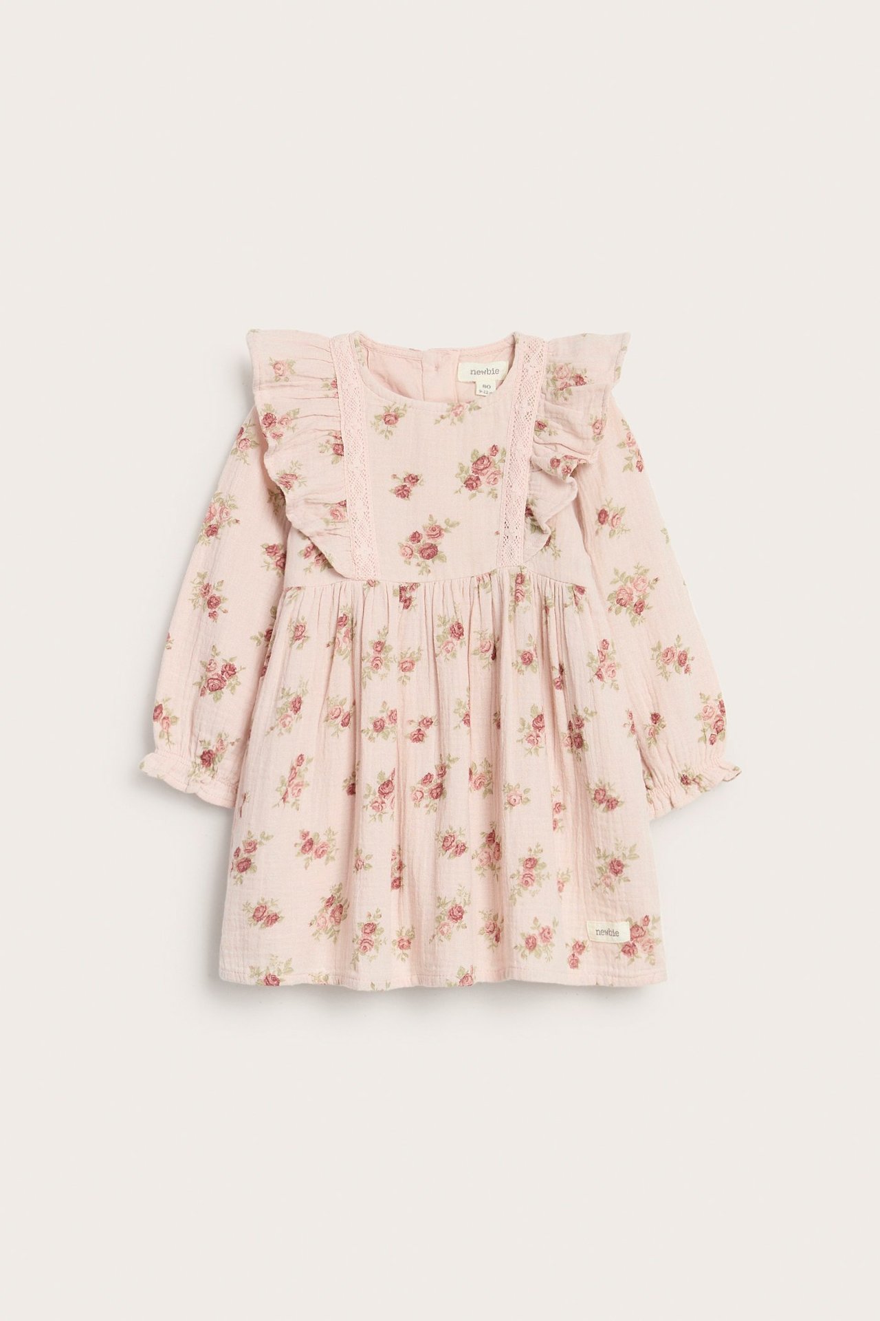 Front view of a light pink floral muslin kid's dress with ruffled shoulders, lace trim, and long puff sleeves.
