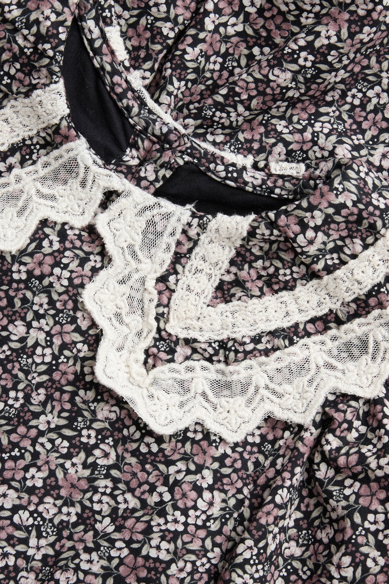 Nahaufnahme eines schwarzen gewebten Baumwollkleides mit Blumenmuster und weißer Spitze.