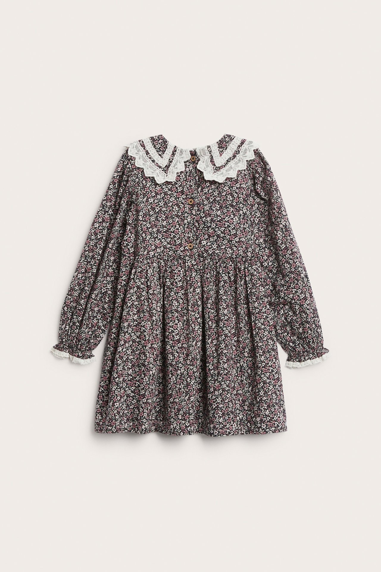 Vorderansicht eines schwarzen geblümten Baumwollkleides für Kinder mit weißem Spitzenkragen und Manschetten.