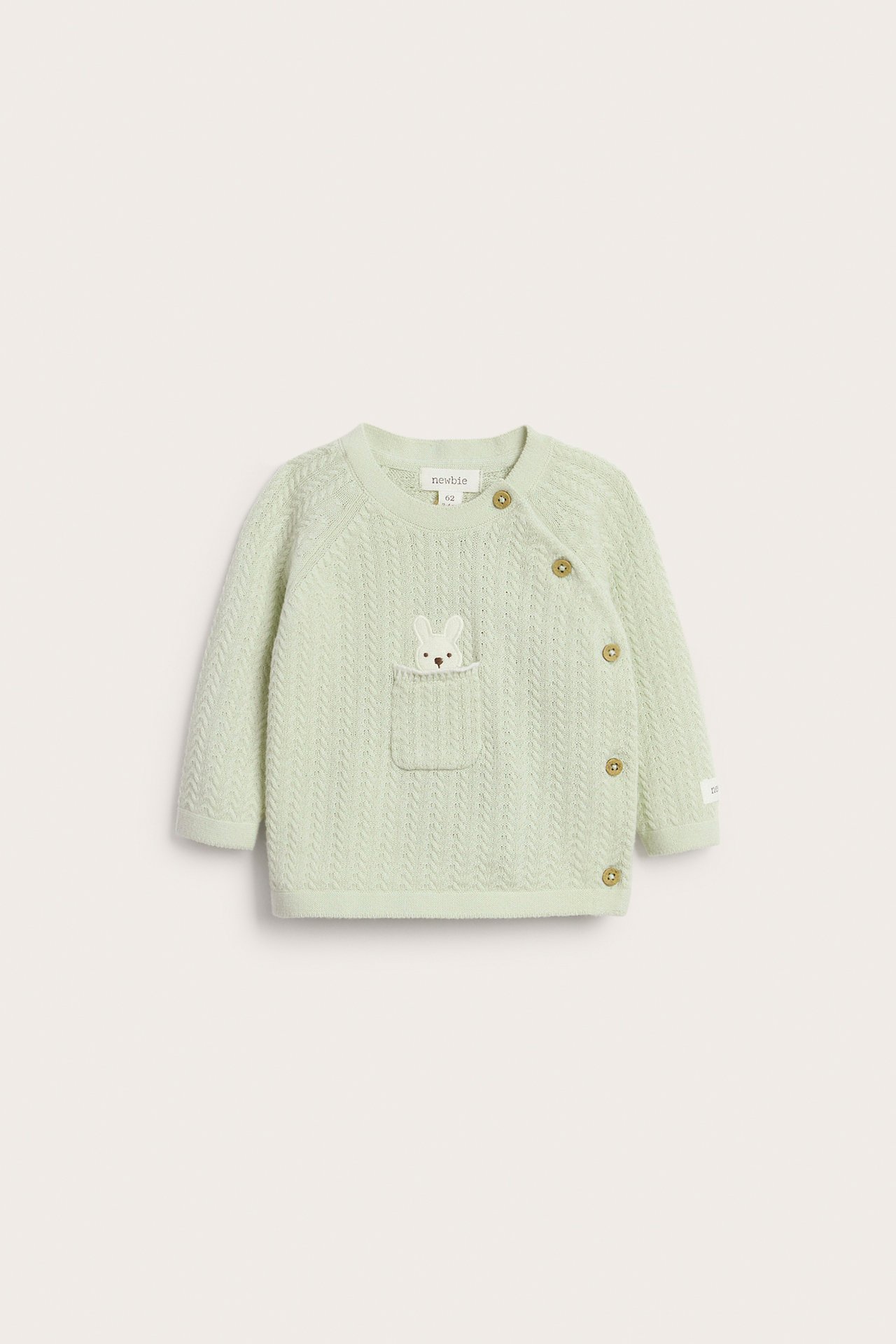 Front view of a light green structured knit baby cardigan with side buttons, a front pocket and bunny embroidery.