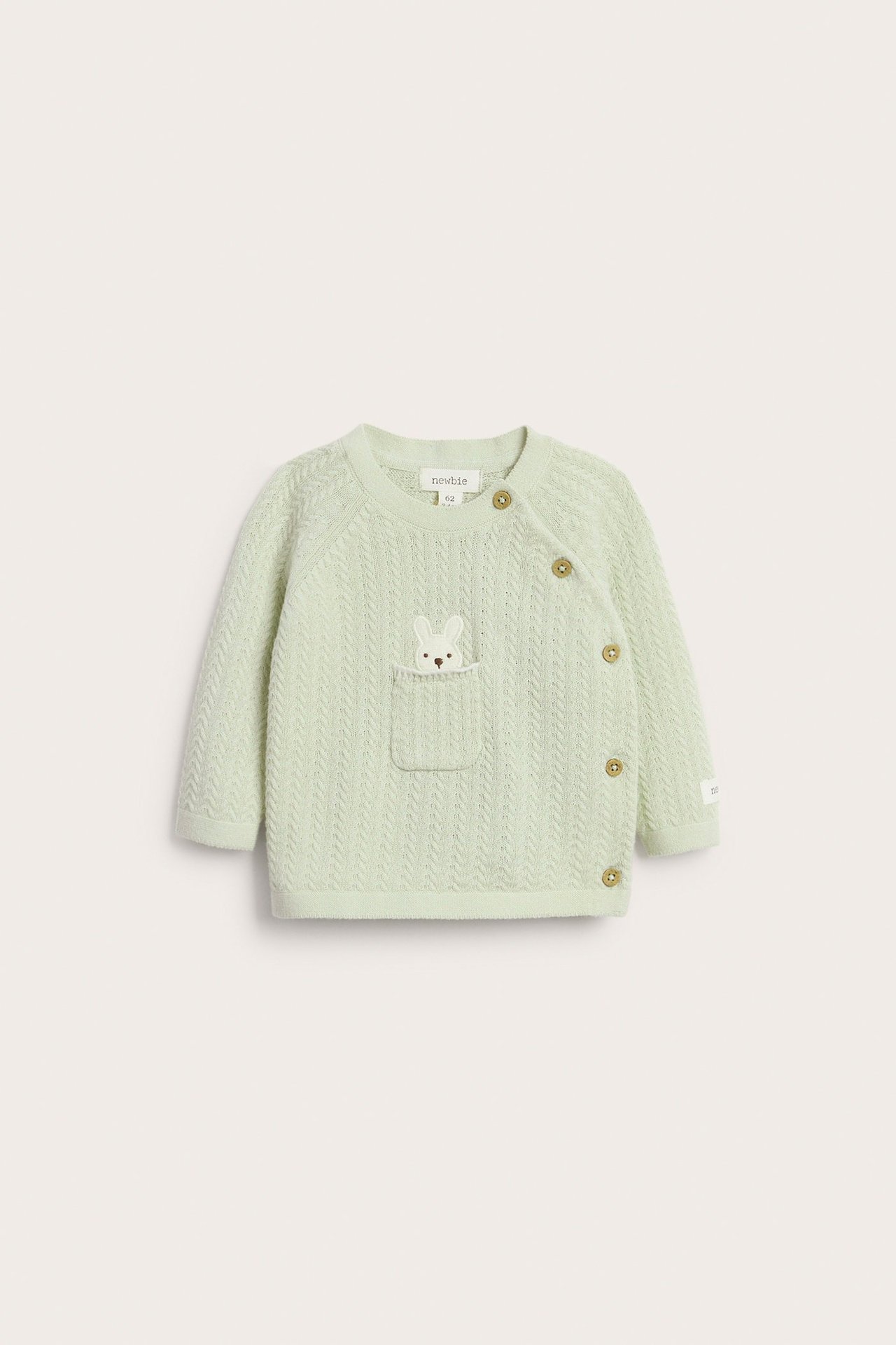 Front view of a light green structured knit baby cardigan with side buttons, a front pocket and bunny embroidery.