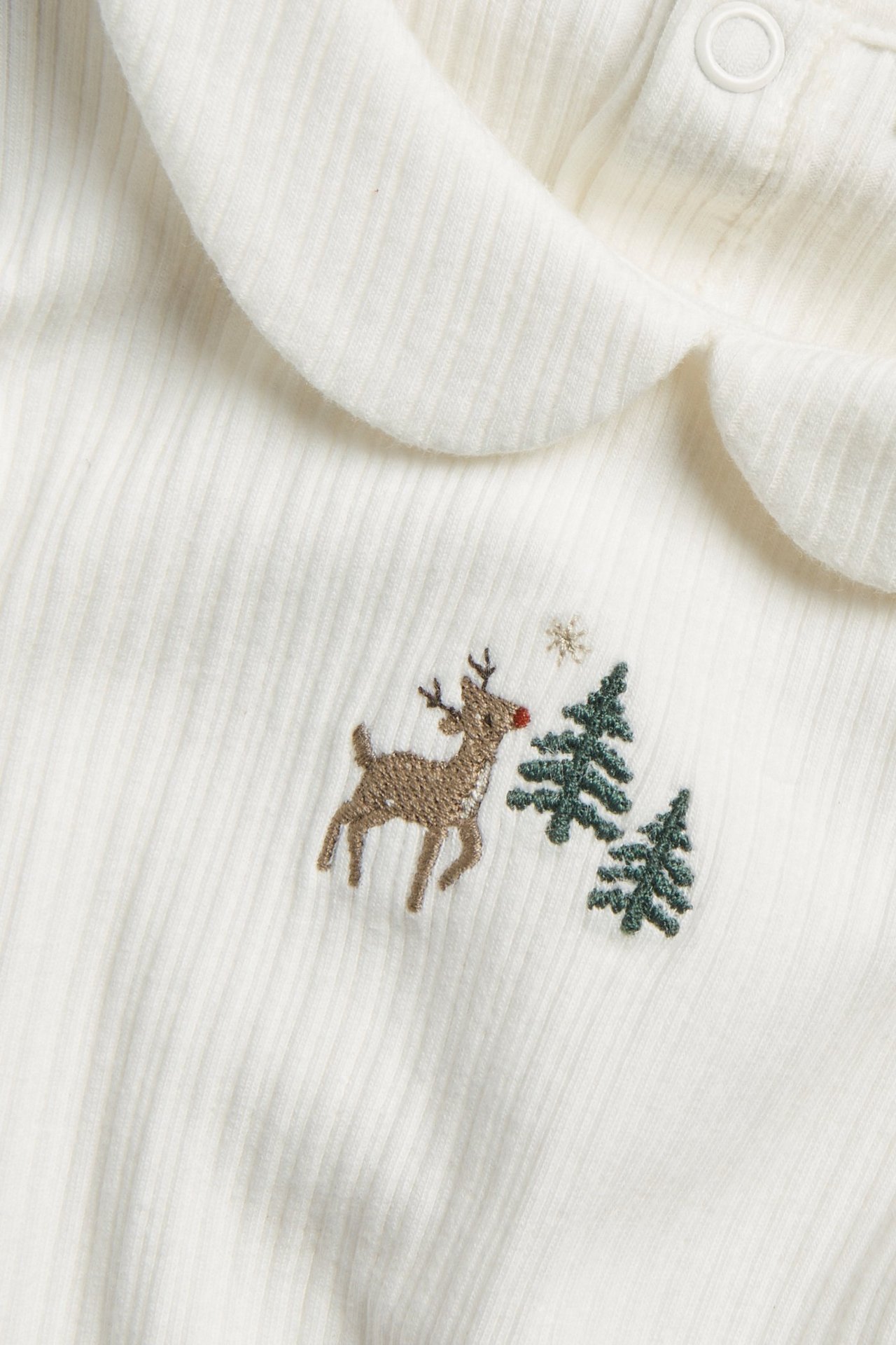 Close-up front view of an off-white ribbed baby Christmas bodysuit with a collar and embroidered reindeer and trees.