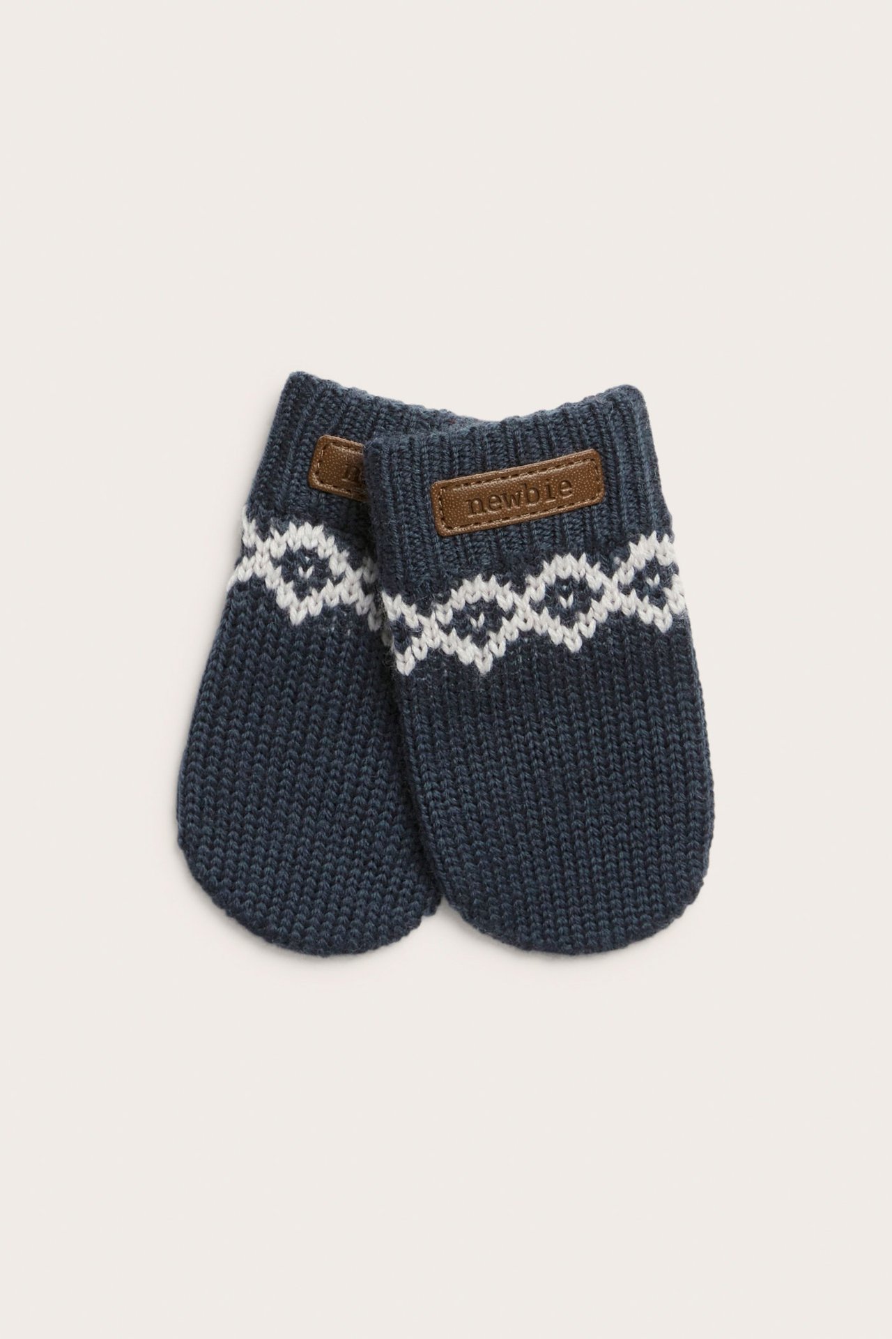 Front view of dark blue wool baby mittens with a white jacquard pattern.