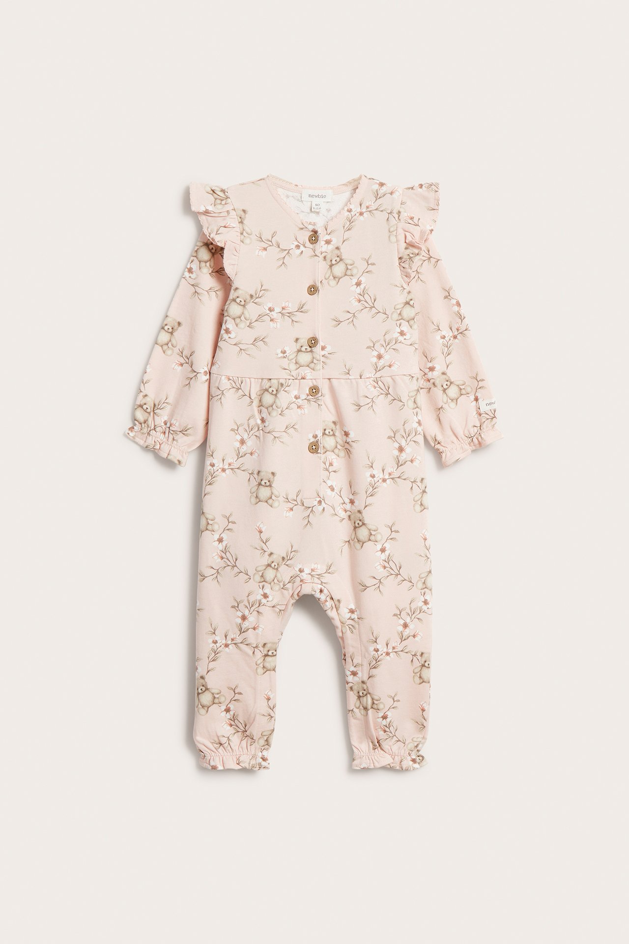 Vorderansicht eines hellrosa Baumwoll-Baby-Jumpsuits mit Blumen- und Teddybär-Print, Rüschen und Vorderknöpfen.