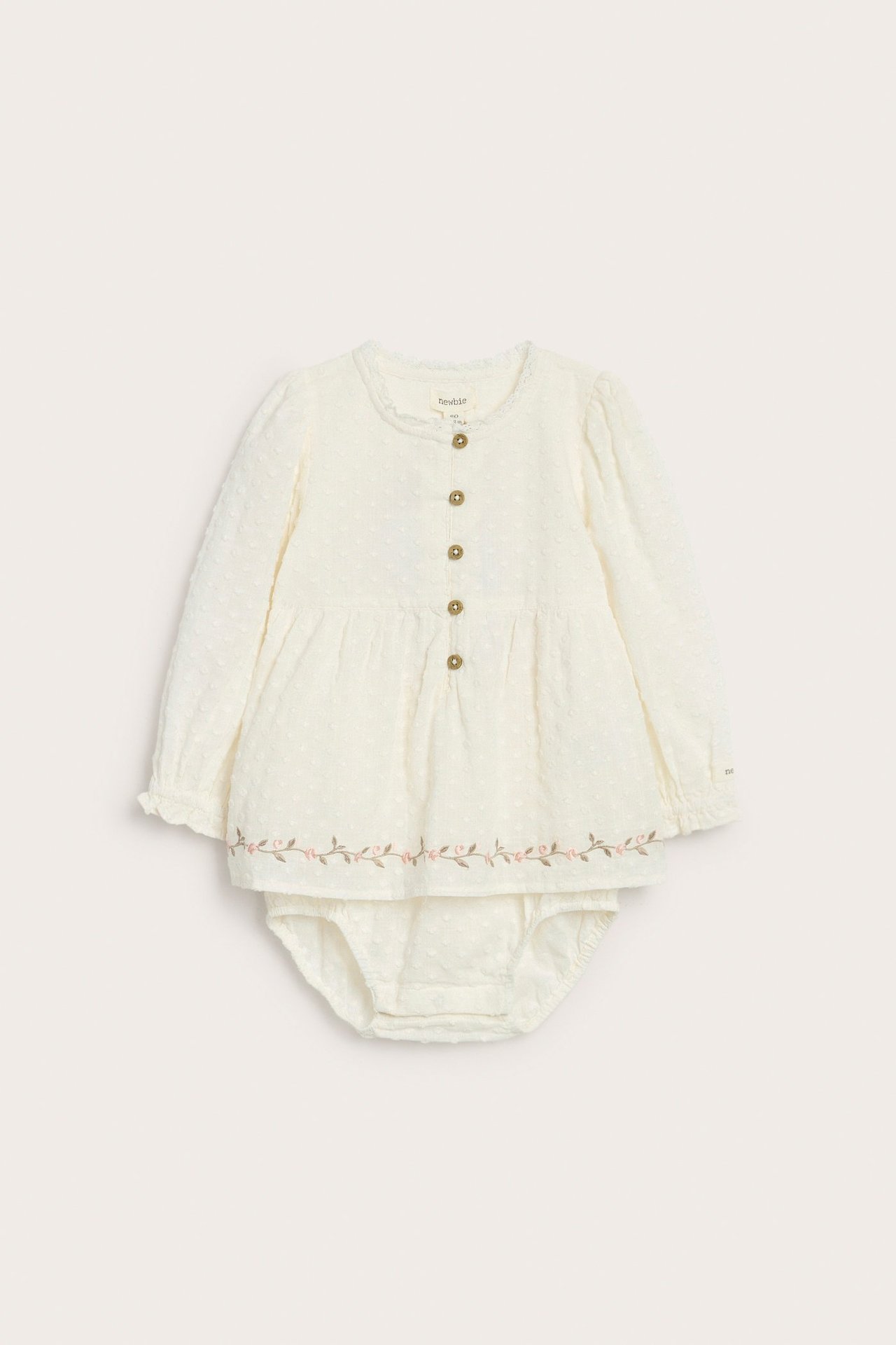 Front view of an offwhite woven cotton baby blouse-bodysuit with floral embroidery and matching bloomers.