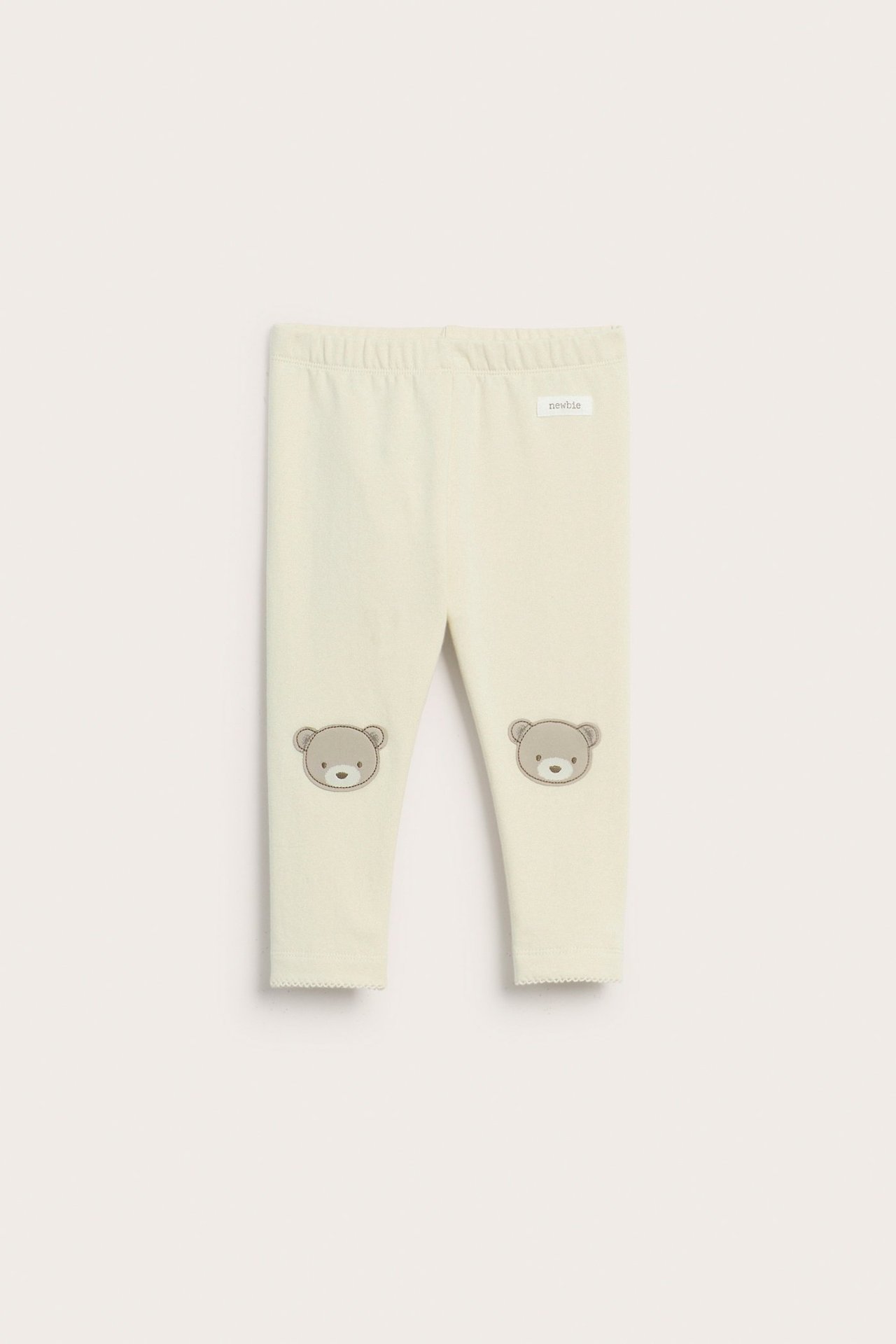 Vorderansicht von hellbeigen Baby-Leggings mit Gummizugbund und braunen Bärenapplikationen an den Knien.