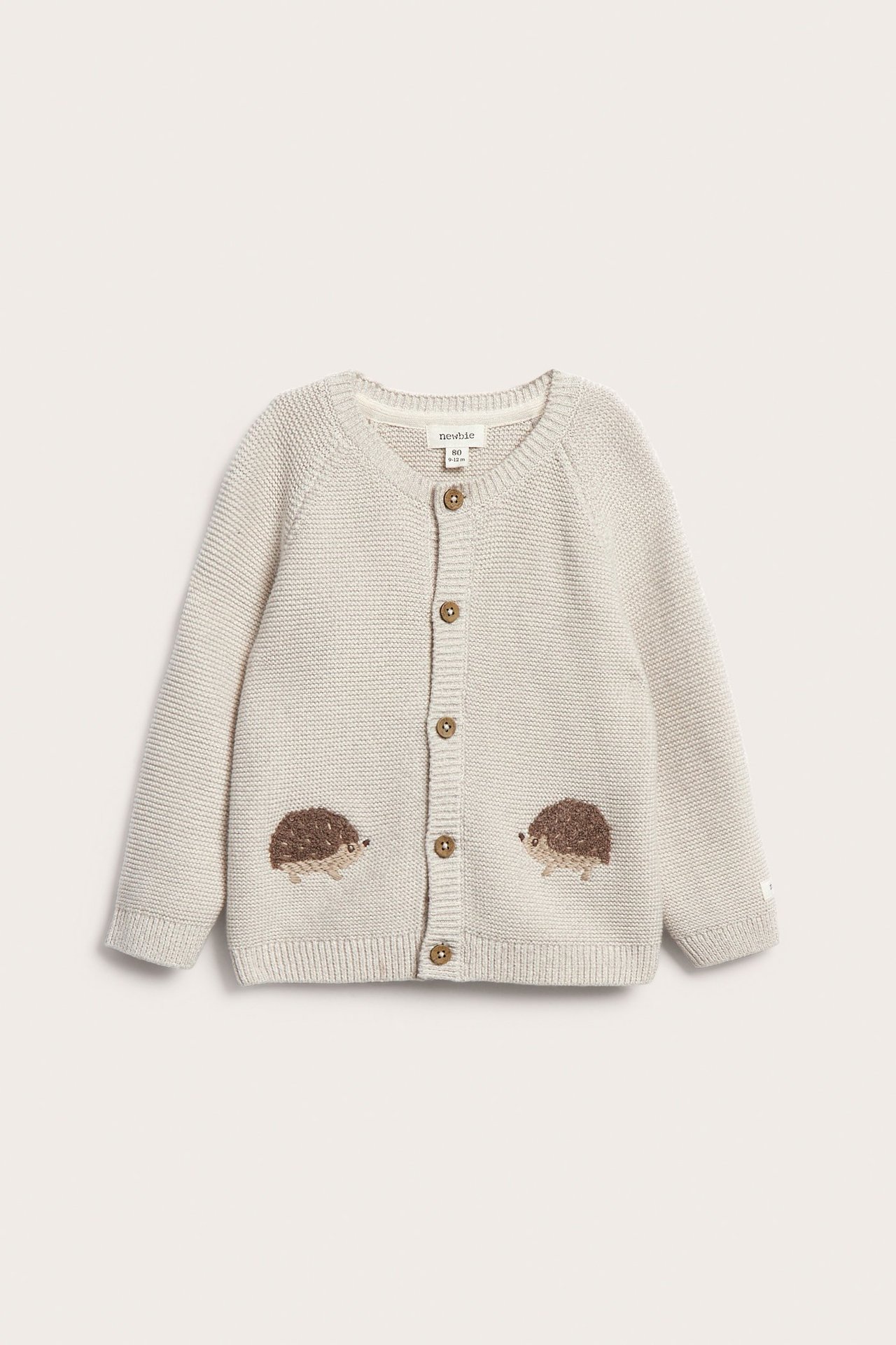 Front view of a beige mélange knitted baby cardigan with five buttons and fluffy hedgehog embroideries.