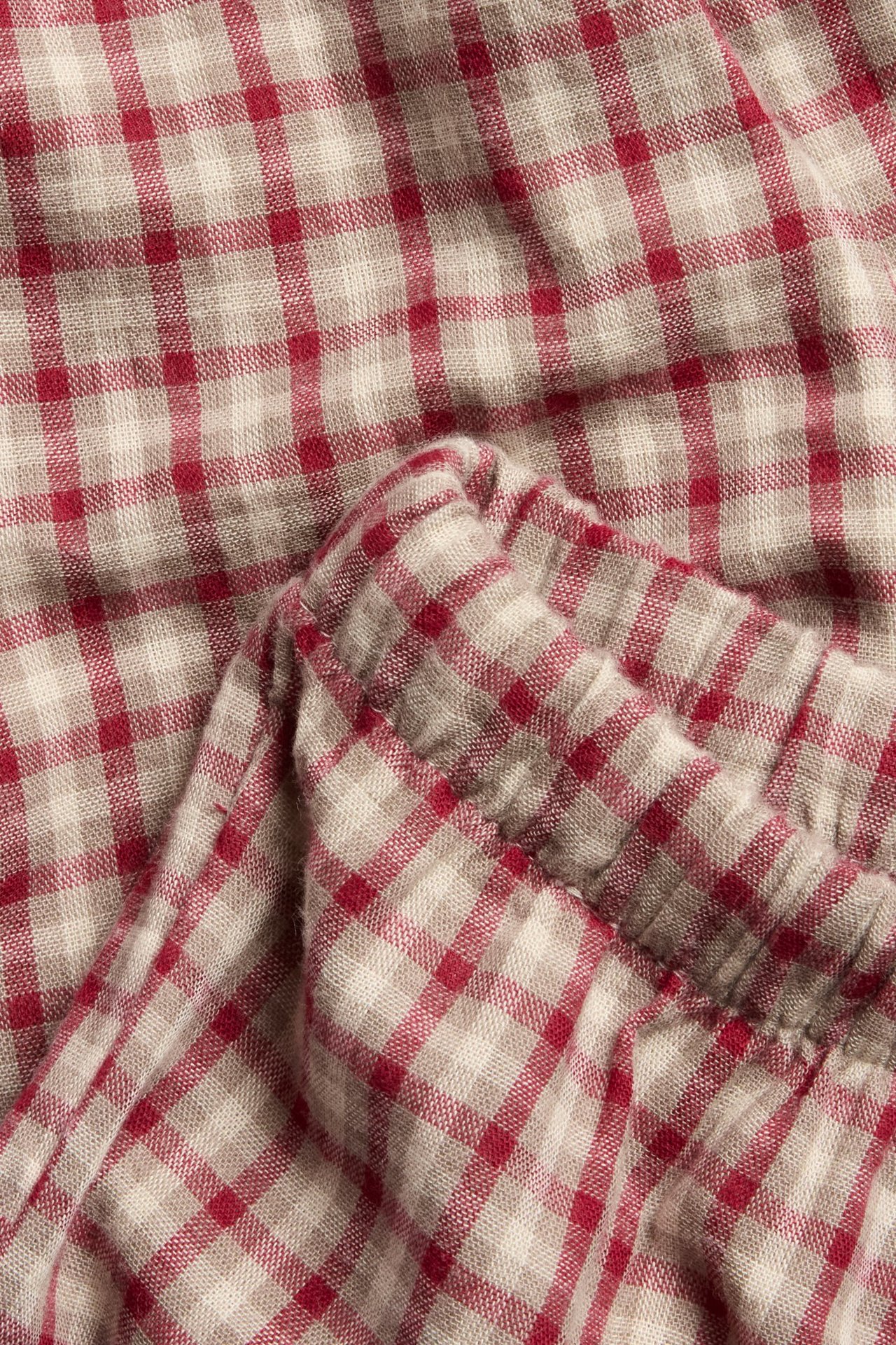 Nahaufnahme von rot-beigen karierten Baumwoll-Leggings mit elastischem, gerafftem Detail.