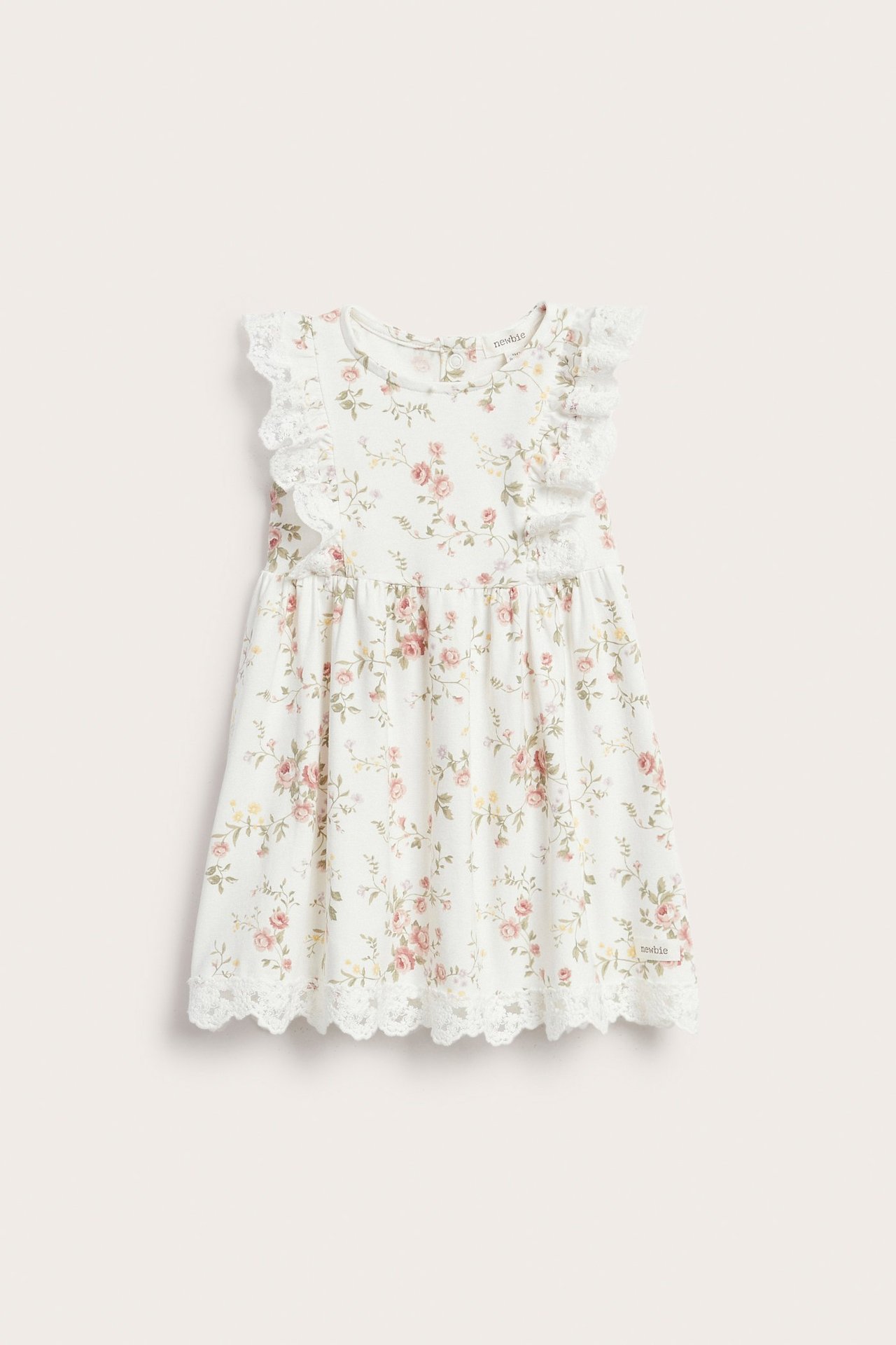 Front view of a kid's off-white sleeveless jersey dress with a pink floral print, ruffle-lace shoulders, and lace hem.