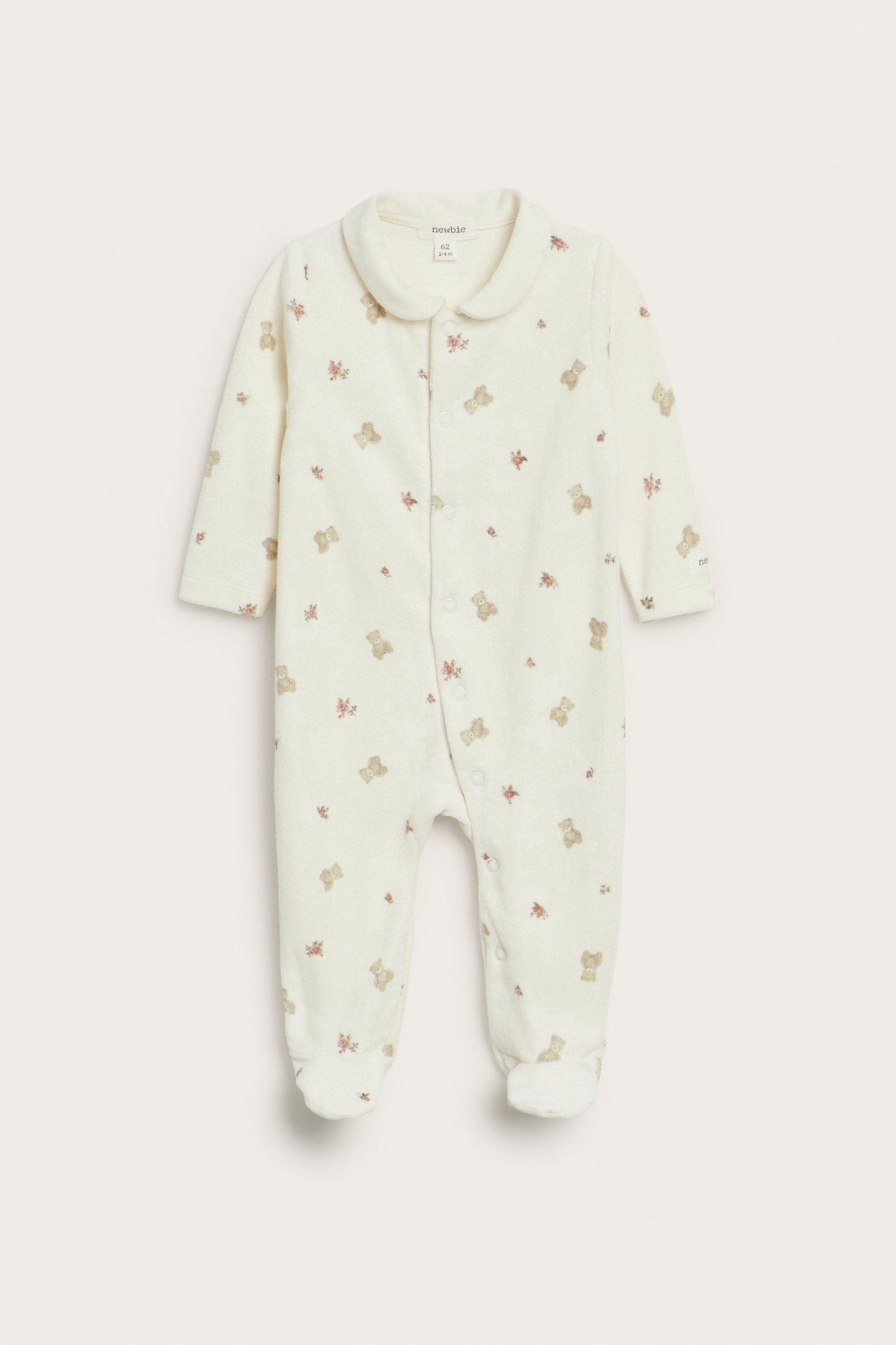 Vorderansicht: Off-white Velours-Babyschlafanzug mit Teddybär- und Blumenmuster, Druckknöpfen und Füßen.