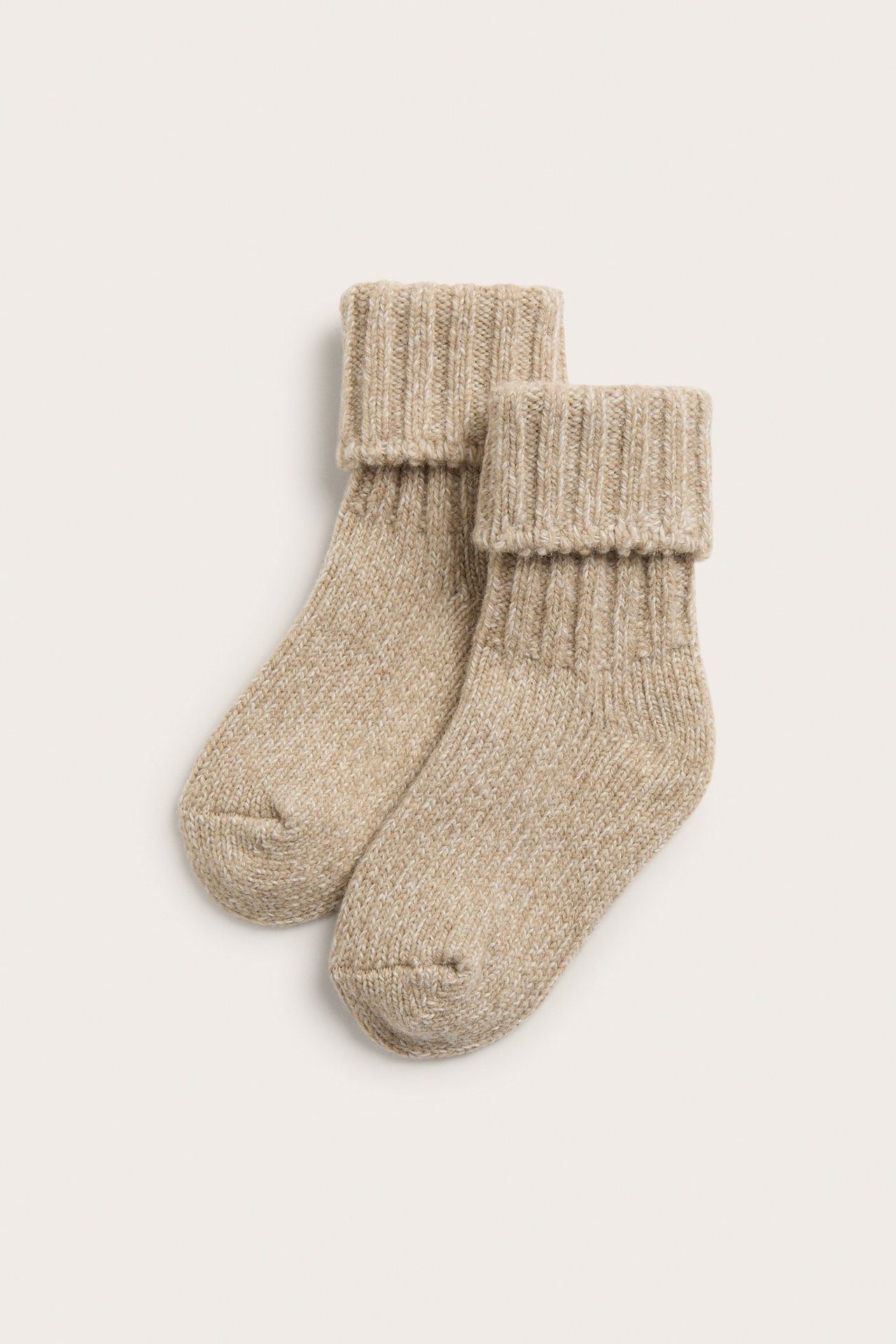 Vorderansicht eines Paares beigefarbener Melange-Wollsocken mit gerippten Bündchen.