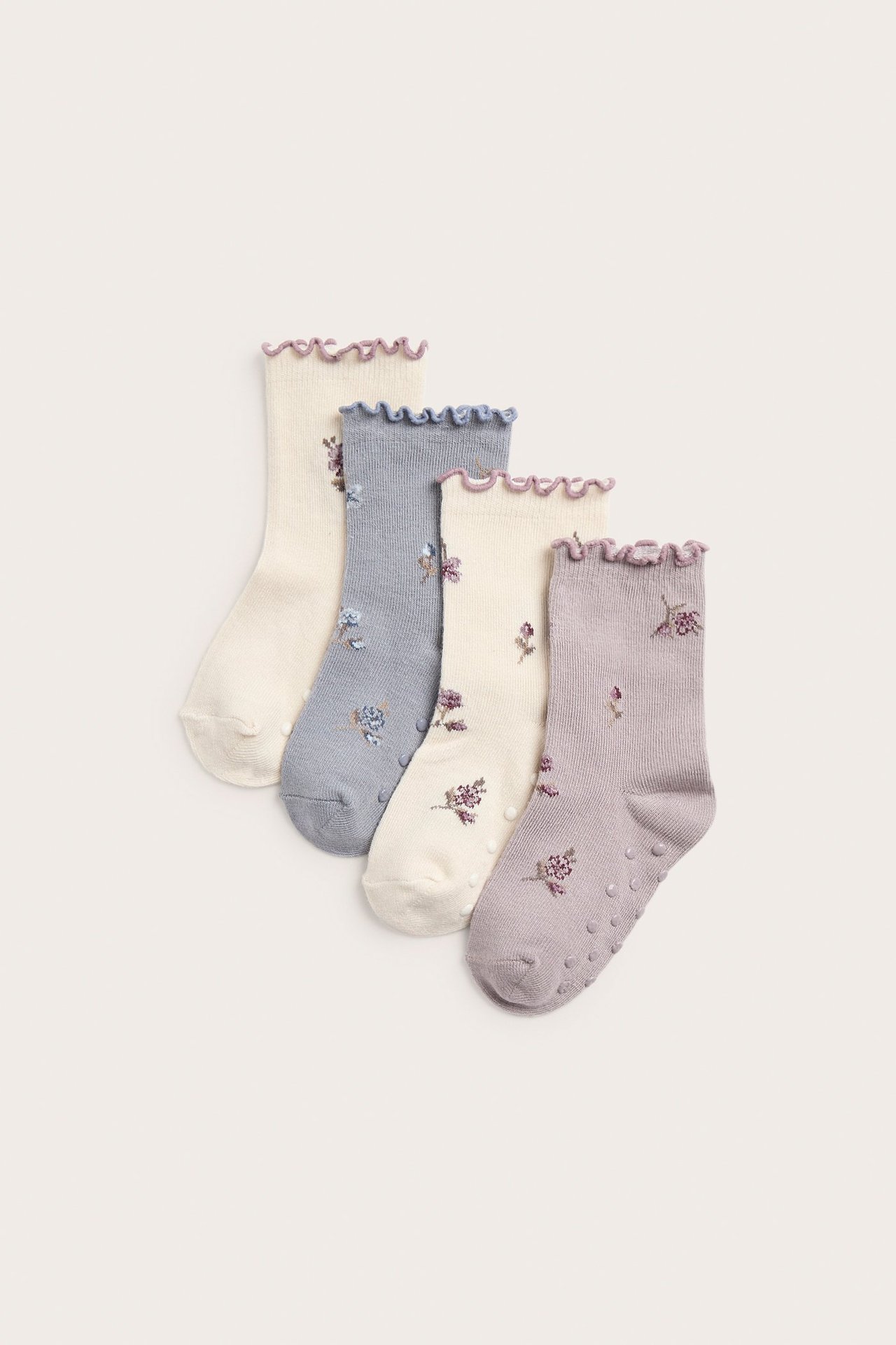 Vier Paar geblümte Socken in Helllila, Blau und Creme, mit Rüschenrändern und Antirutsch.