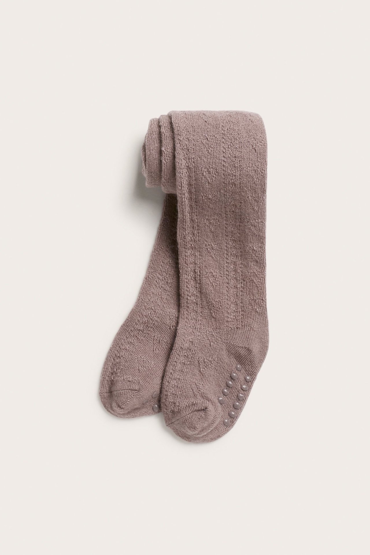 Ansicht von oben auf gefaltete dunkelrosa Baby-Strumpfhosen mit Lochmuster und Anti-Rutsch-Sohlen.