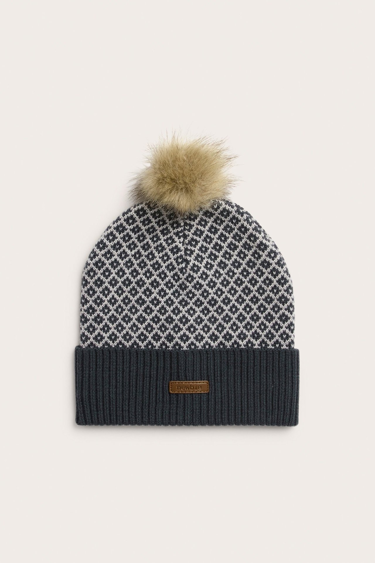 Vorderansicht: Dunkelblaue und weiße Jacquard-Wollmütze mit Rippstrickbündchen und hellbraunem Kunstfell-Pompon.