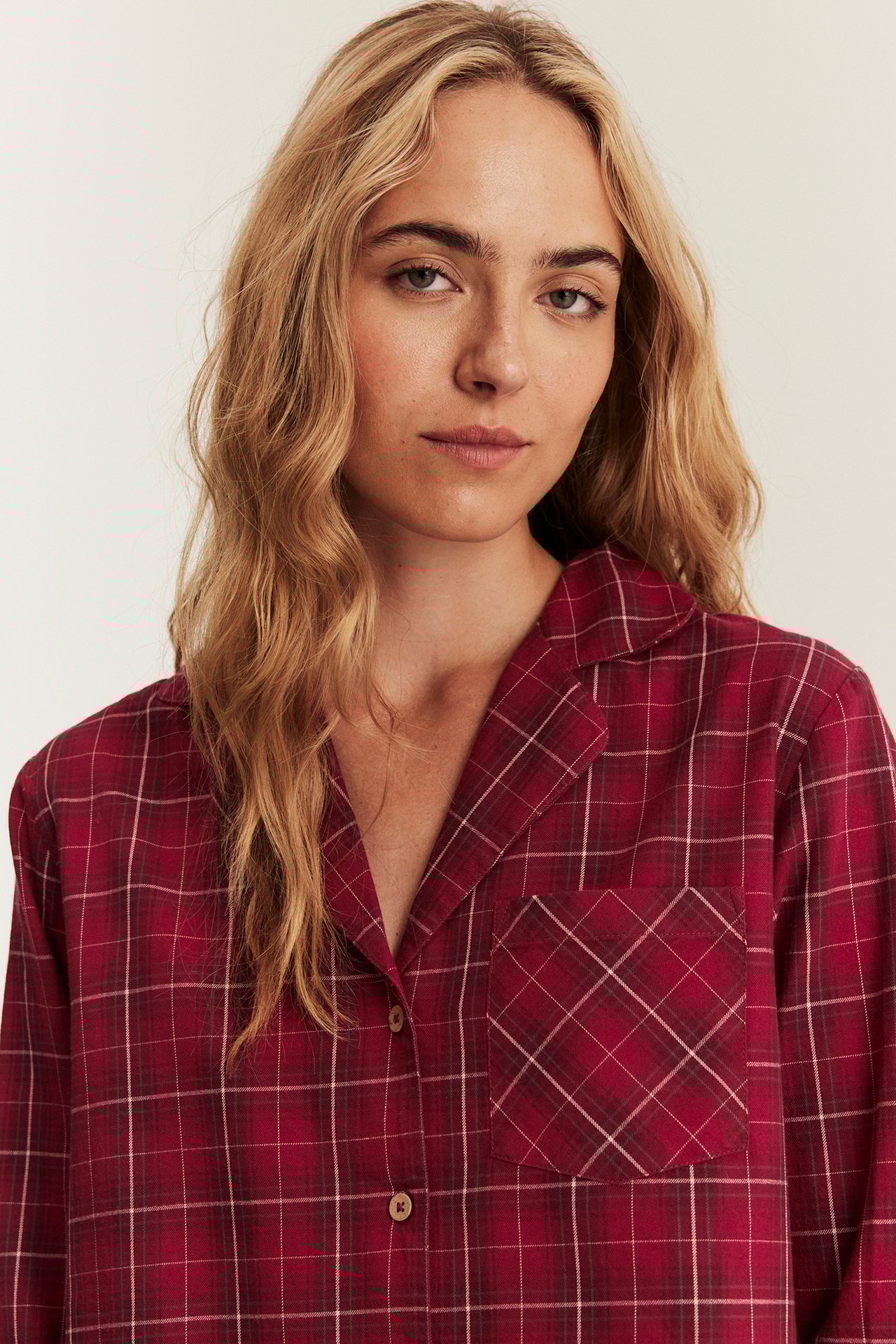 Nahaufnahme, Frau in rotem, kariertem Flanell-Pyjama-Shirt mit Kragen, Knöpfen und Tasche.