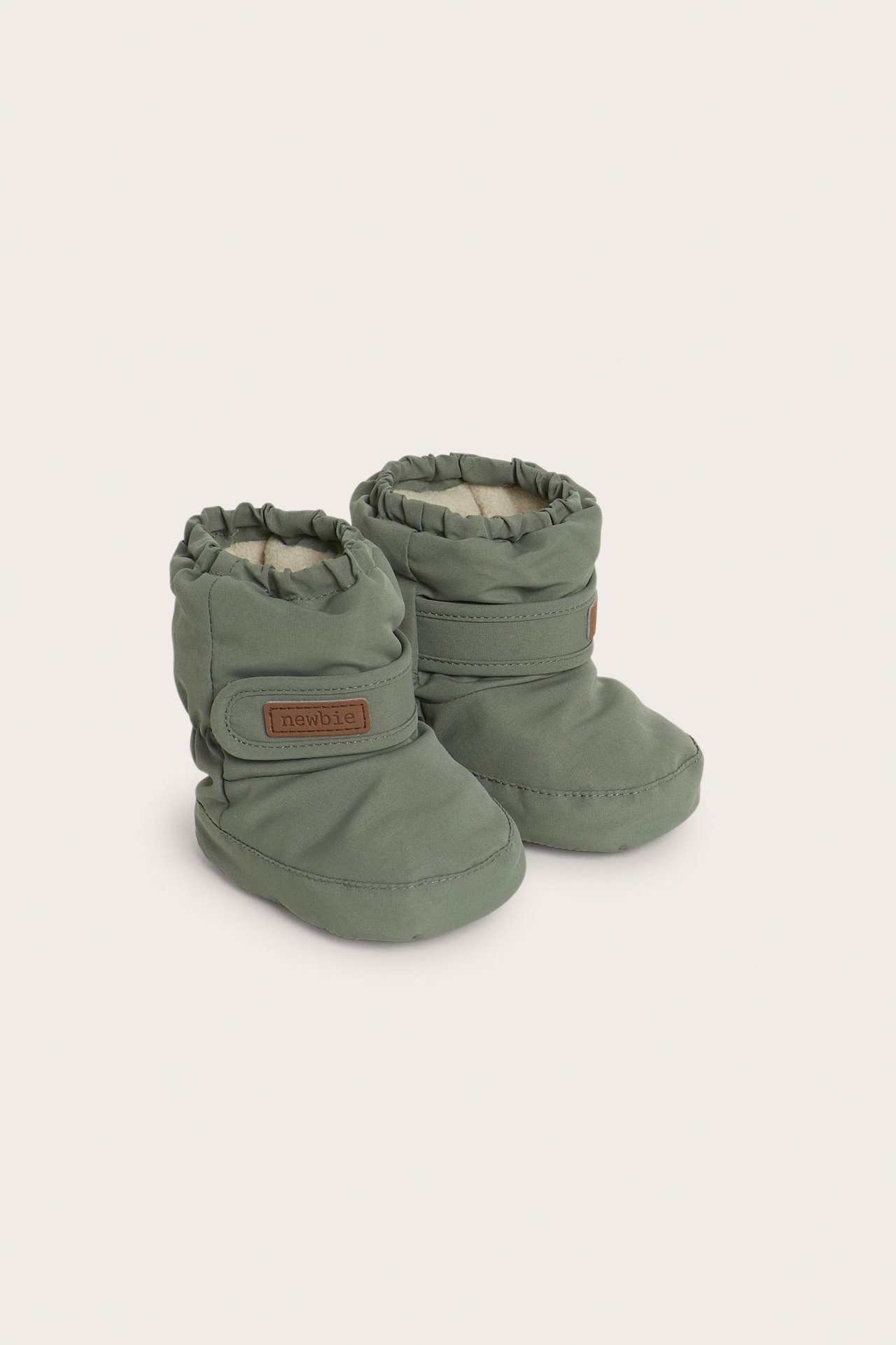 Front view of a pair of dark green padded baby booties with elasticated tops and adjustable straps.