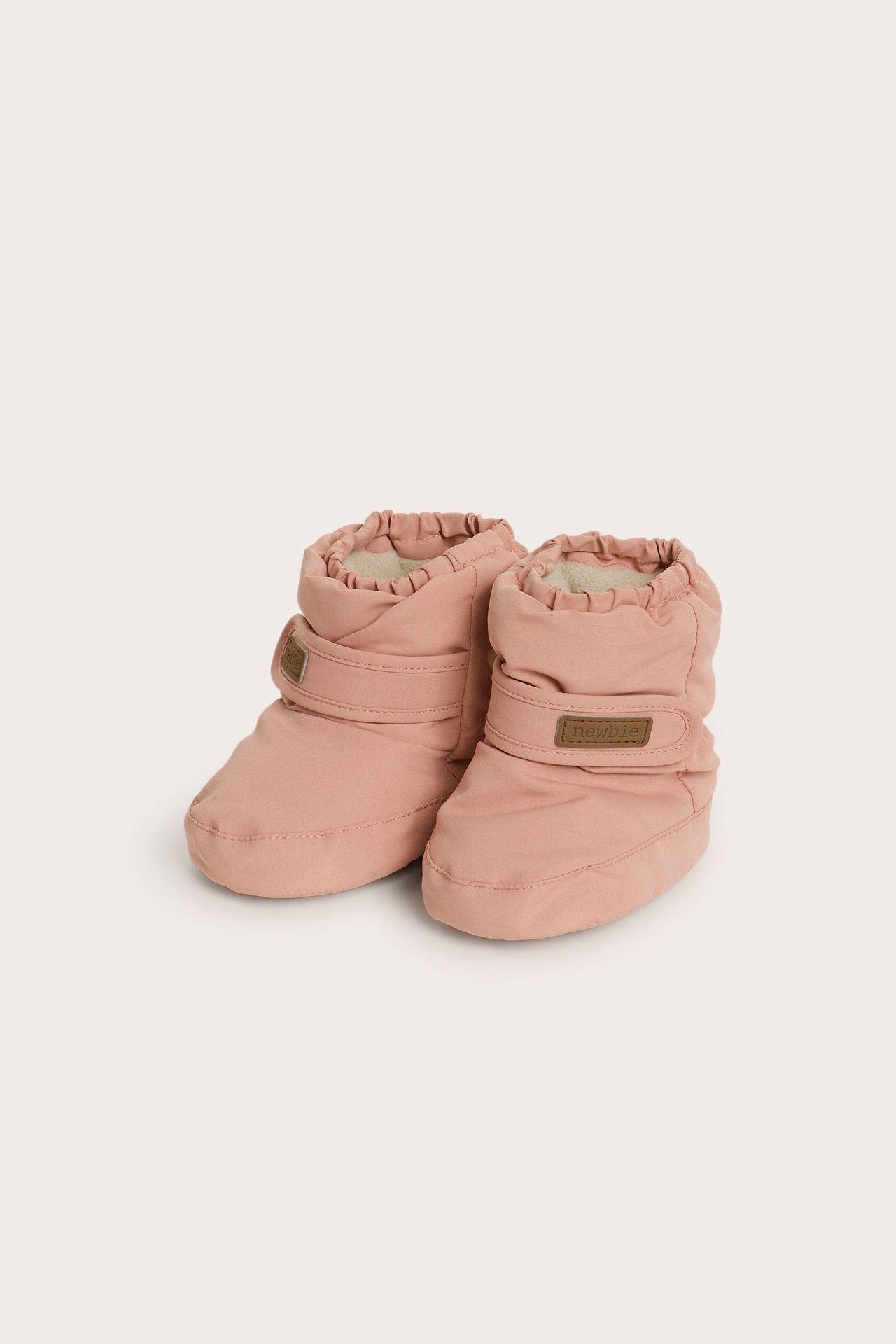 Front view of pink padded baby booties with fleece lining, elasticated top, and hook-and-loop straps.