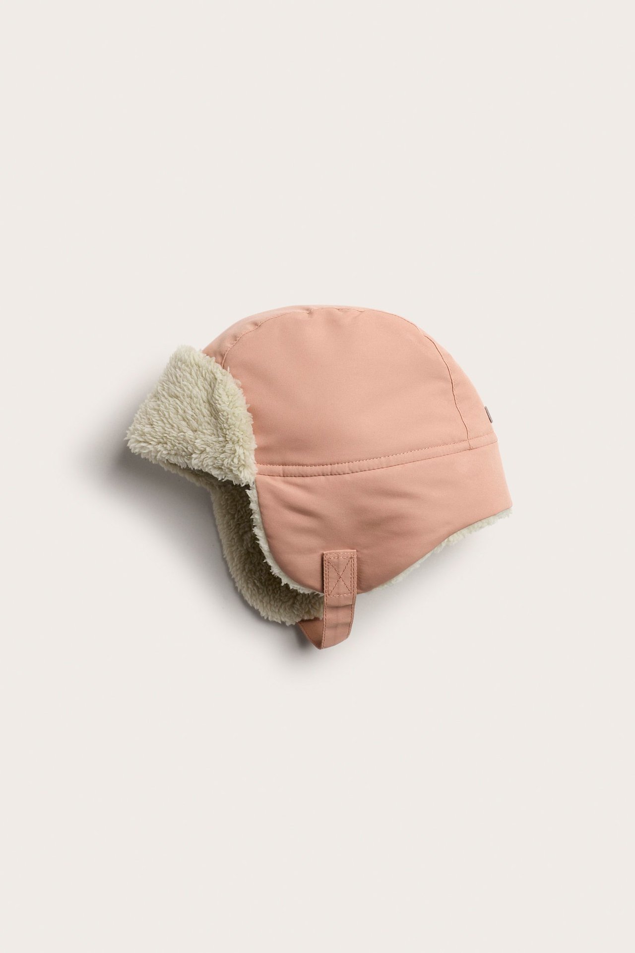Seitenansicht einer rosa Baby-Wintermütze mit weichem Teddyfutter und Klettverschluss.