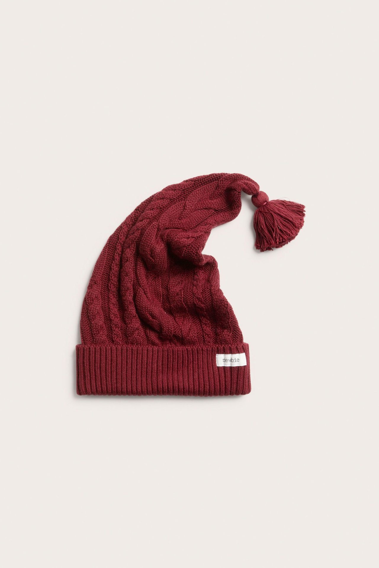 Front view of a red cable knit Santa hat with a tassel.