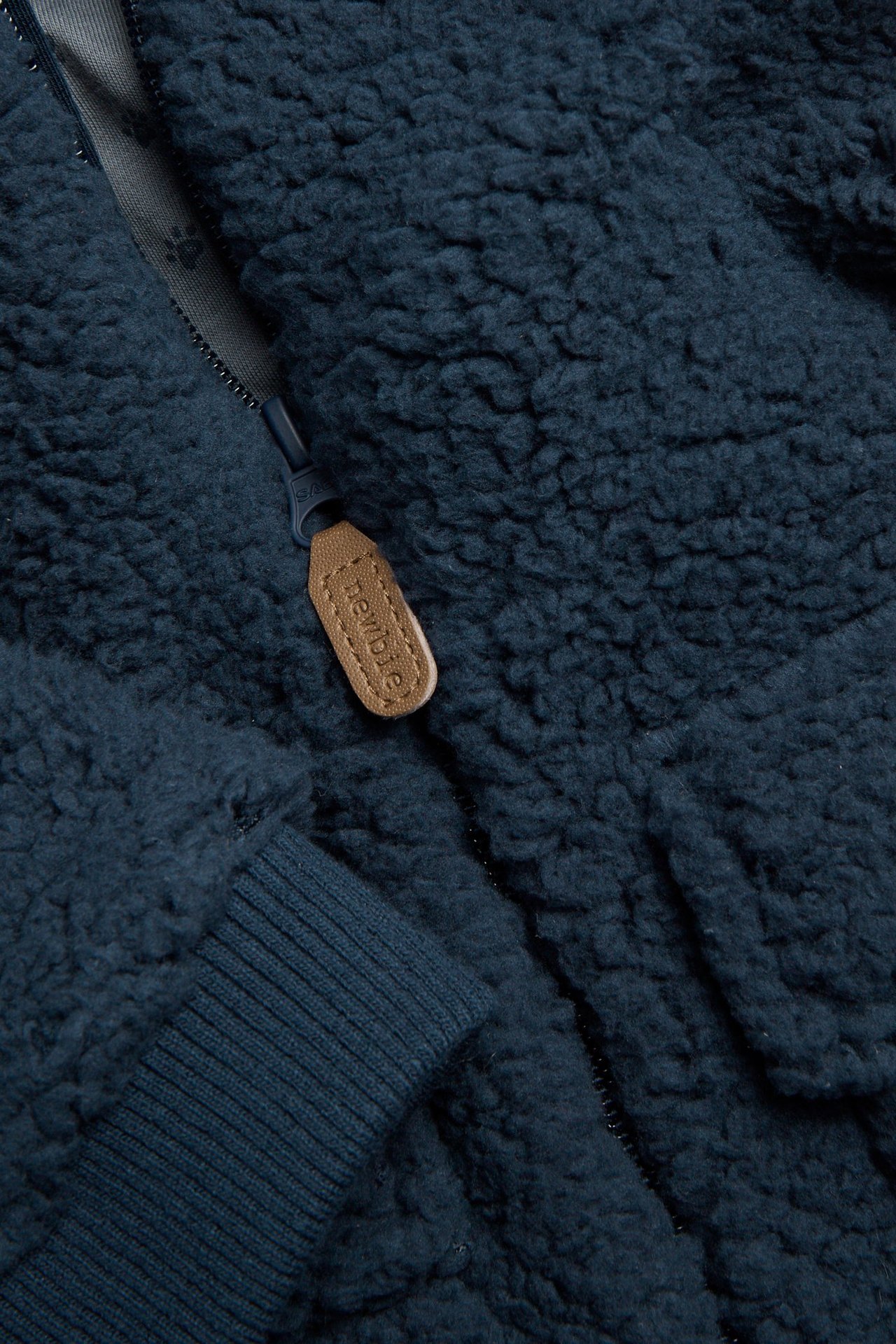 Nahaufnahme einer dunkelblauen Pile-Jacke mit Reißverschluss und Rippenbündchen.