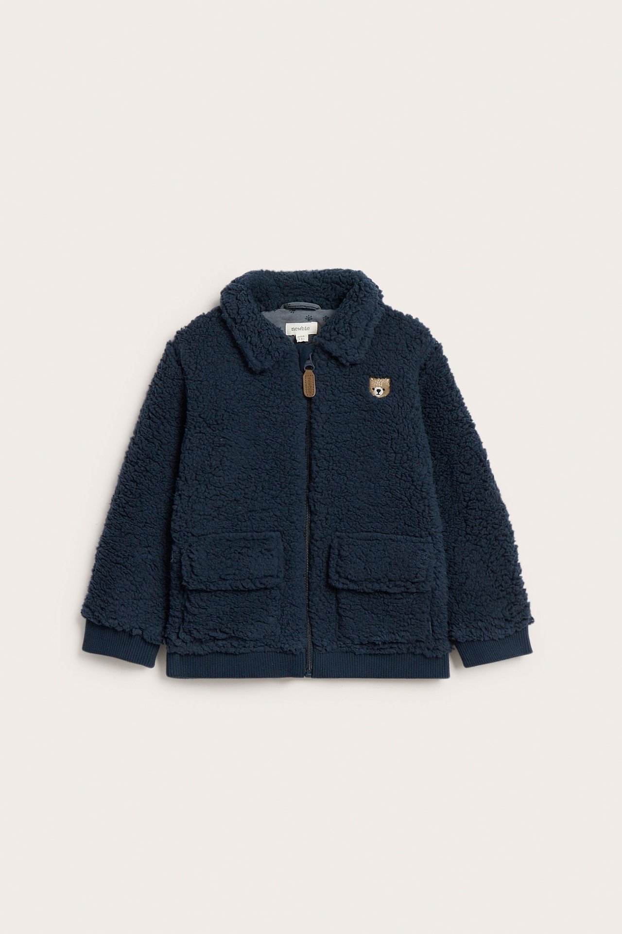 Front view: Kid's dark blue pile jacket with collar, zipper, two patch pockets, and bear embroidery.