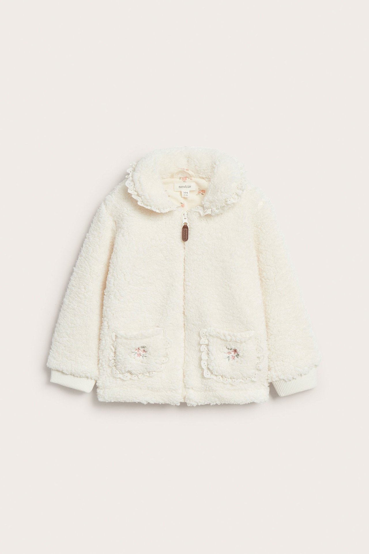 Off-white kid's pile jacket, front view, with lace collar, zipper, and embroidered pockets.