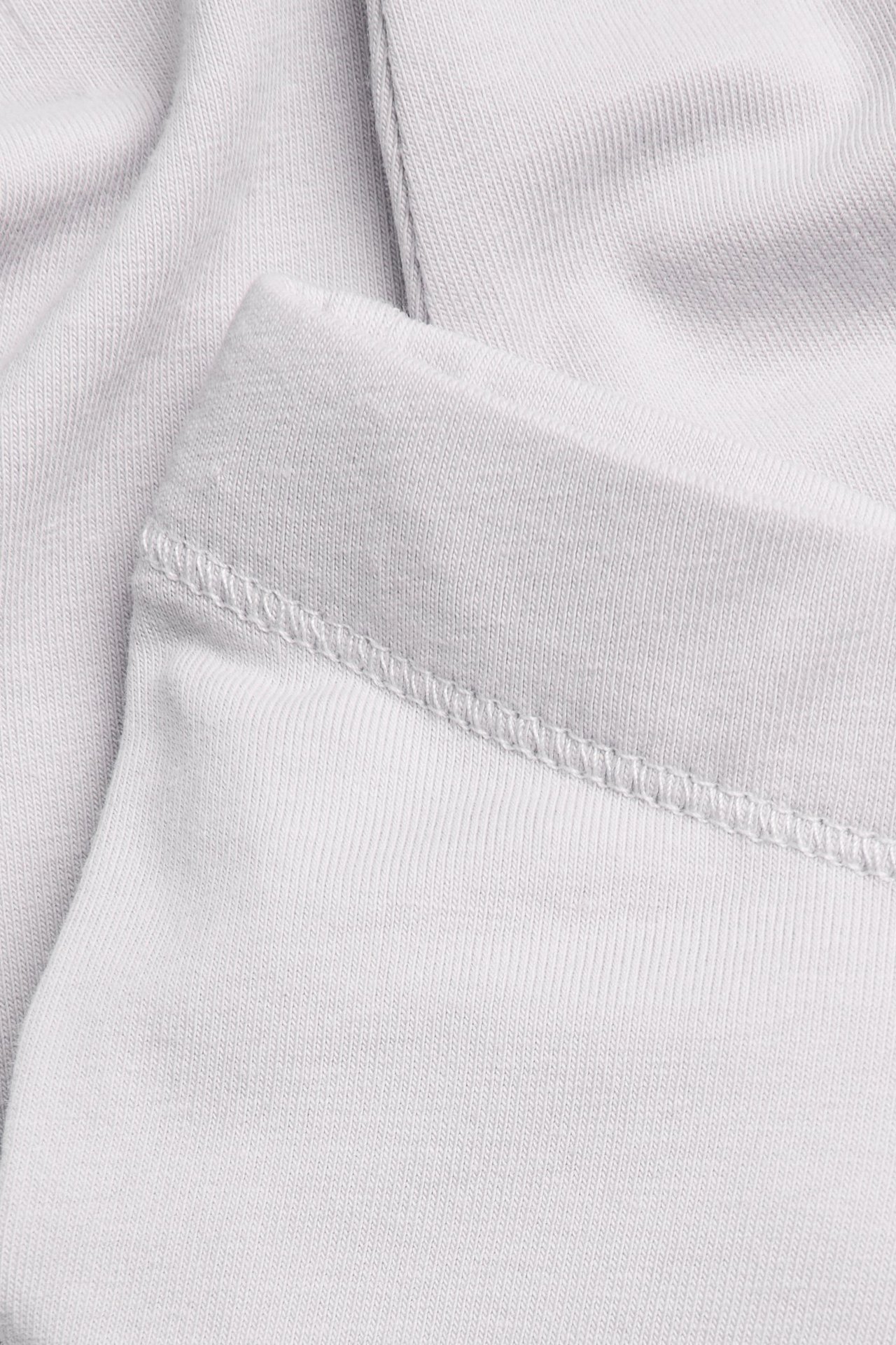 Nahaufnahme helllila gerippter Leggings, zeigt den elastischen Bund mit Steppnähten.