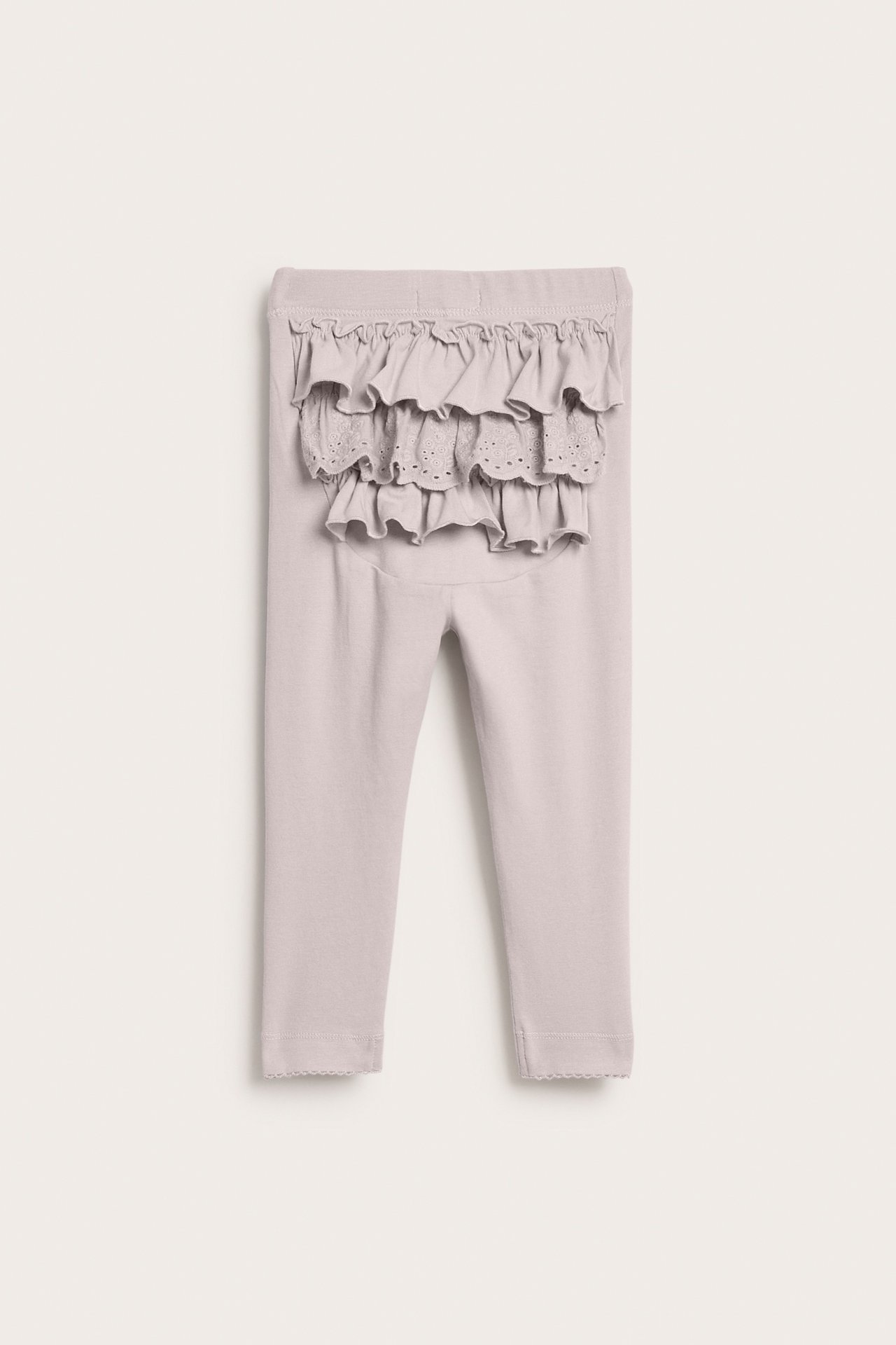 Back view of light gray baby leggings with eyelet ruffles and scalloped cuffs.