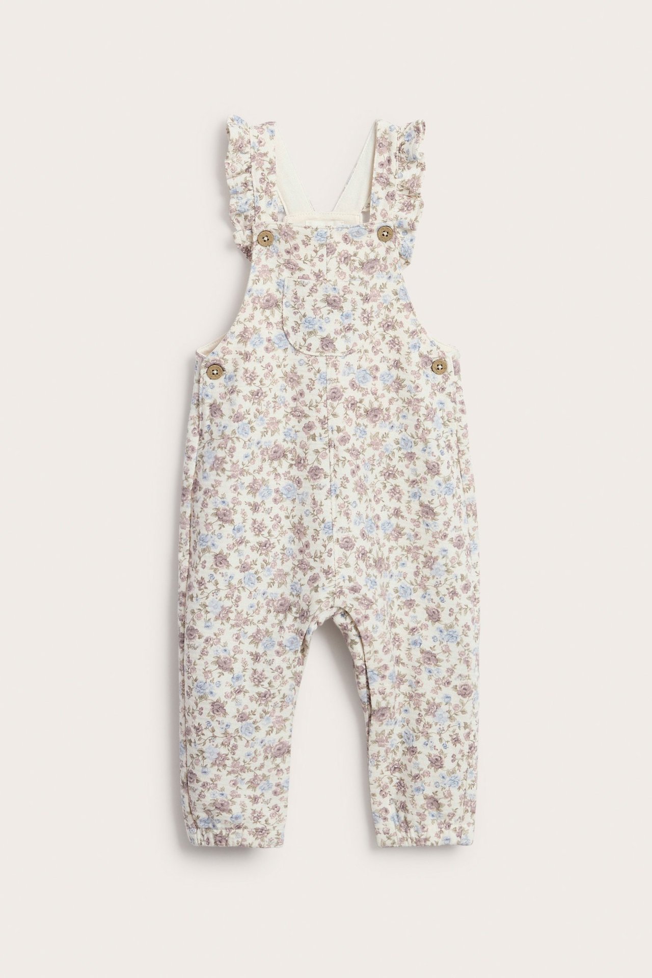 Vorderansicht von off-white Baby-Jersey-Latzhose mit lila-blauem Blumenmuster, Rüschenträgern und seitlichen Knöpfen.