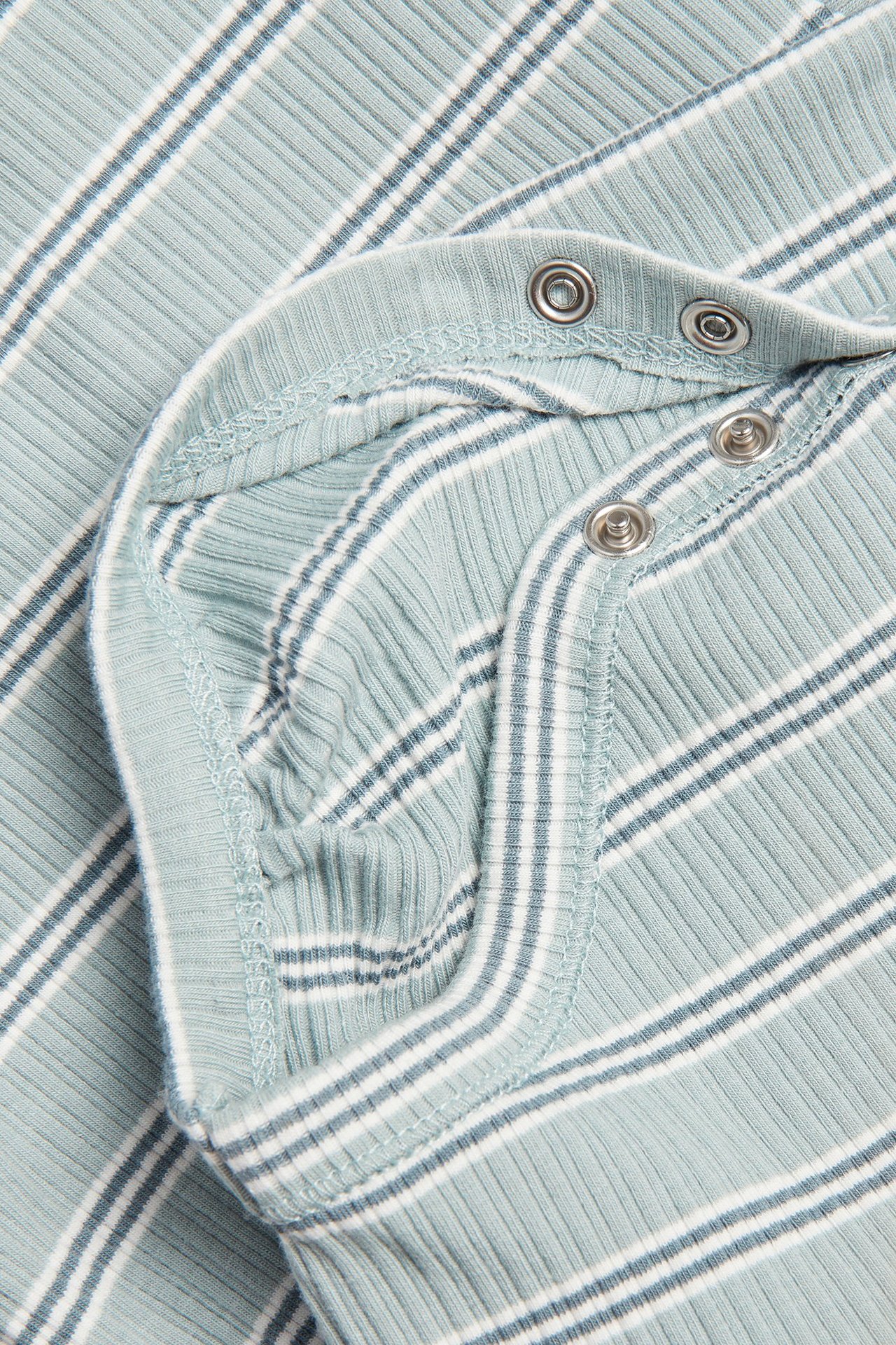 Nahaufnahme eines hellgrünen gestreiften Ripp-Babybodys mit Druckknöpfen an der Schulter.