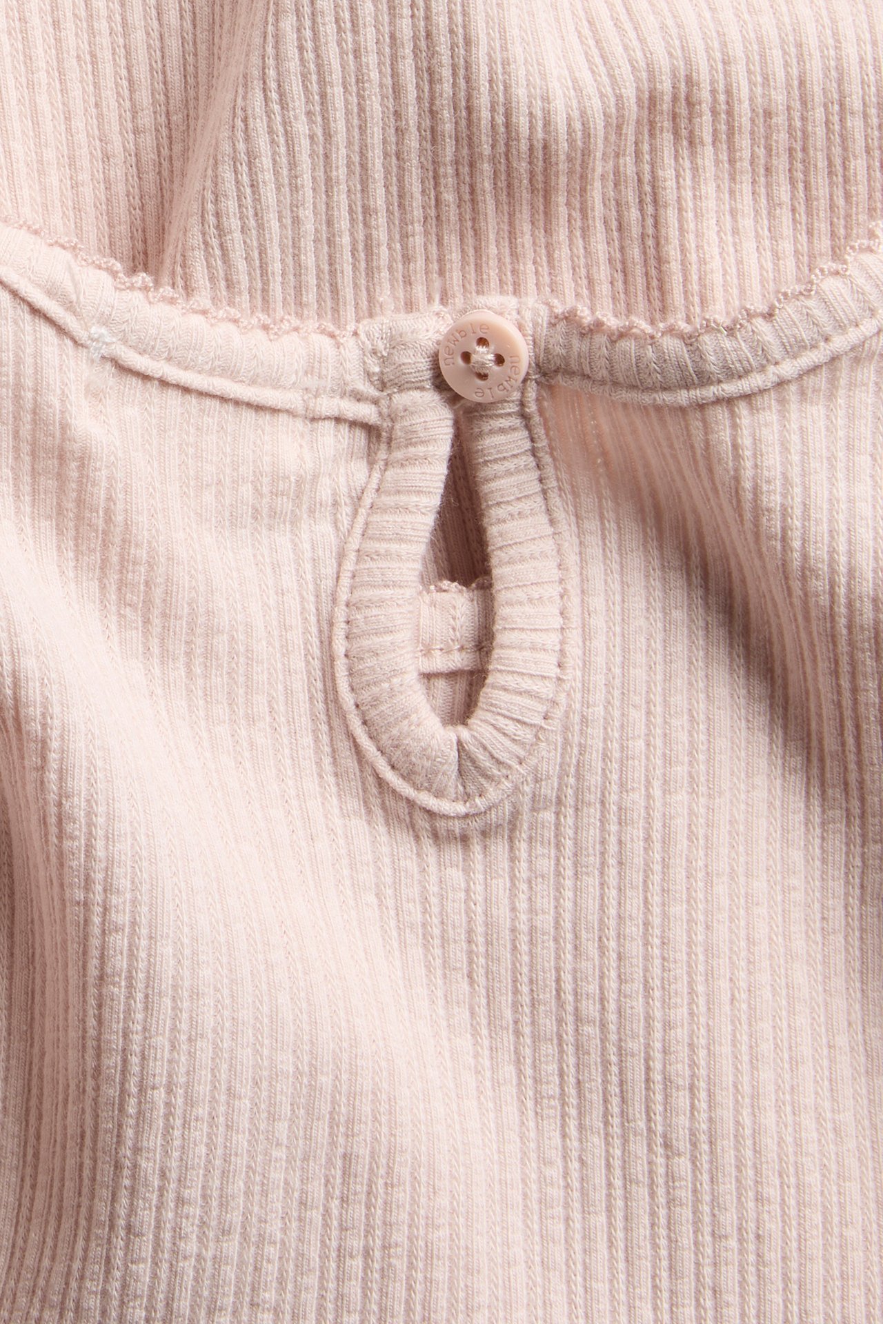 Close-up back view of a light pink ribbed jersey baby bodysuit with a keyhole opening and a single button.