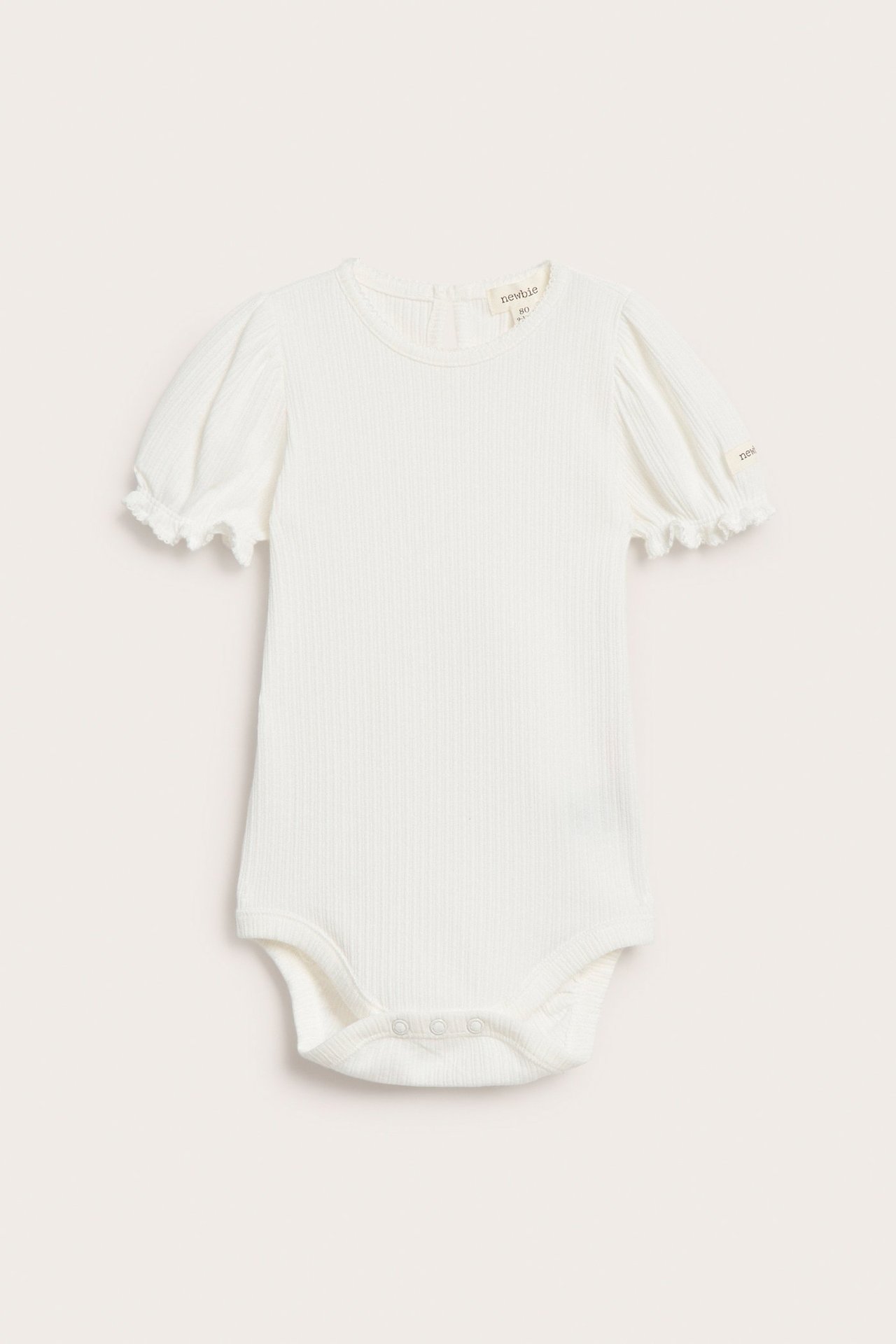 Front view of an off-white ribbed jersey baby bodysuit with short puff sleeves and snap fasteners.