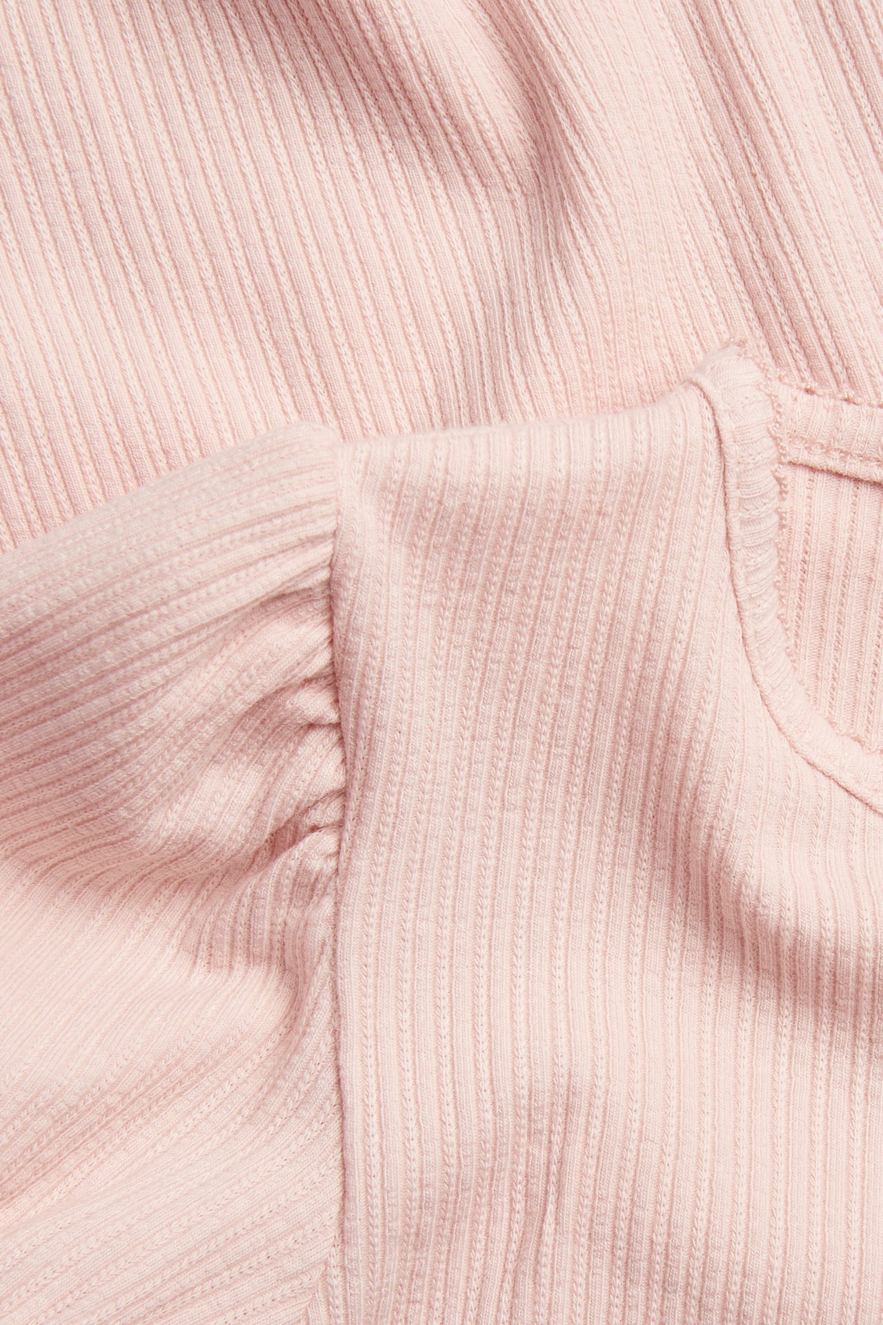 Close-up of a light pink ribbed jersey short-sleeved top featuring gathered puff sleeves.