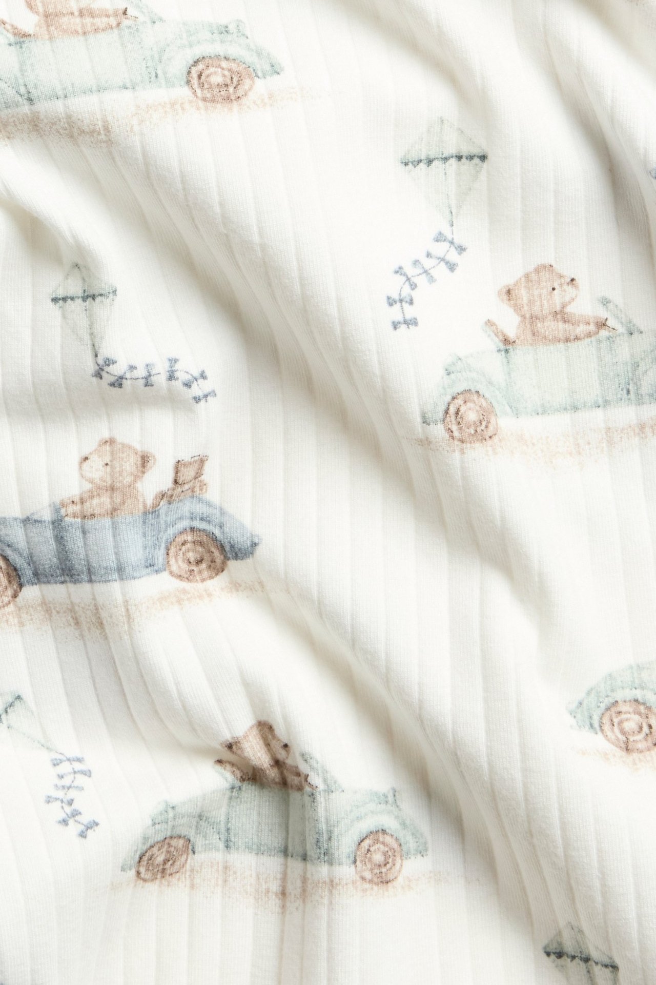 Long-sleeved ribbed body in offwhite with car print, snap buttons on shoulder and crotch.